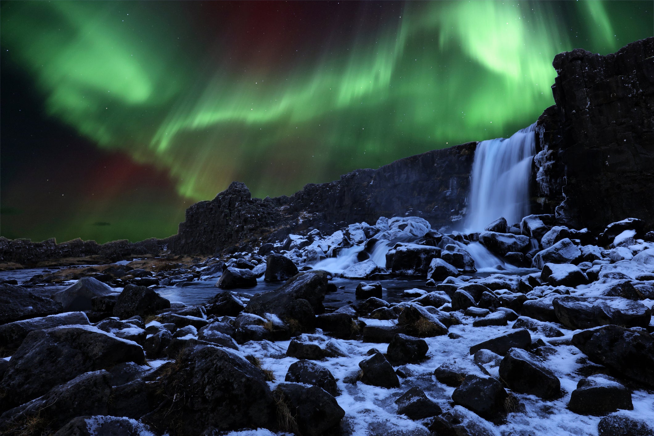 The Aurora Borealis lights up the sky above a waterfall in Thingvellir National Park
