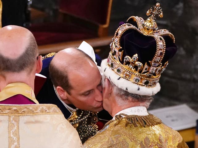 El príncipe Guillermo, príncipe de Gales, besa a su padre, el rey Carlos III, con la corona de San Eduardo, durante la ceremonia de coronación del rey.