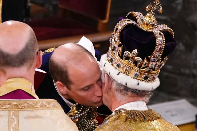 El príncipe Guillermo, príncipe de Gales, besa a su padre, el rey Carlos III, con la corona de San Eduardo, durante la ceremonia de coronación del rey.