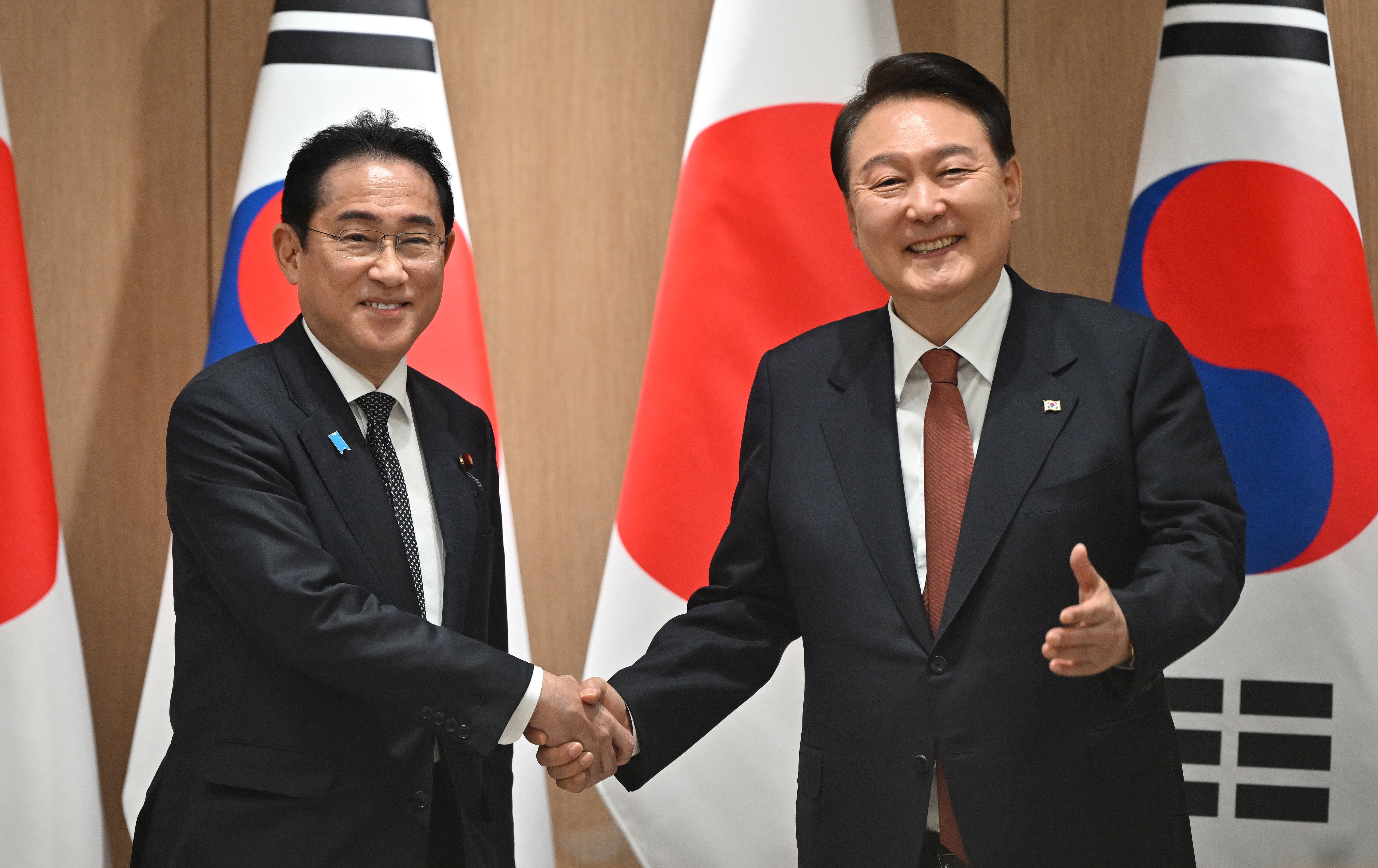 Yoon Suk Yeol shakes hands with Fumio Kishida (left) during their meeting at the former’s presidential office