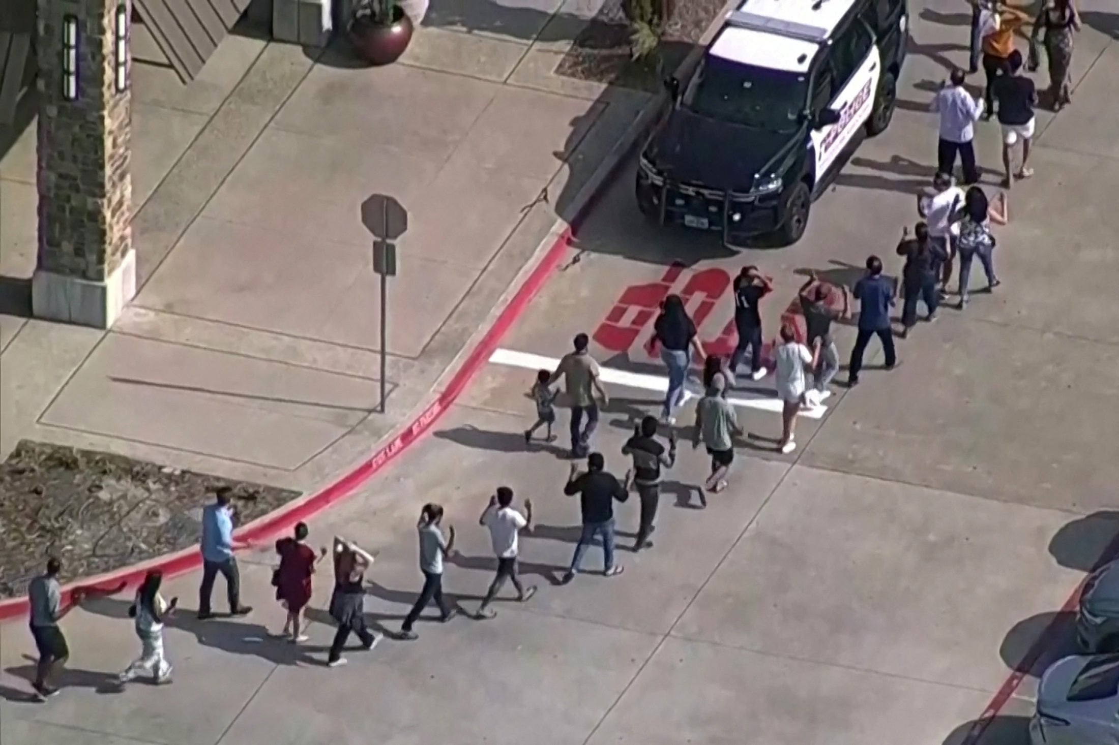 Survivors of the Allen mall mass shooting are escorted away from the scene by police officers.