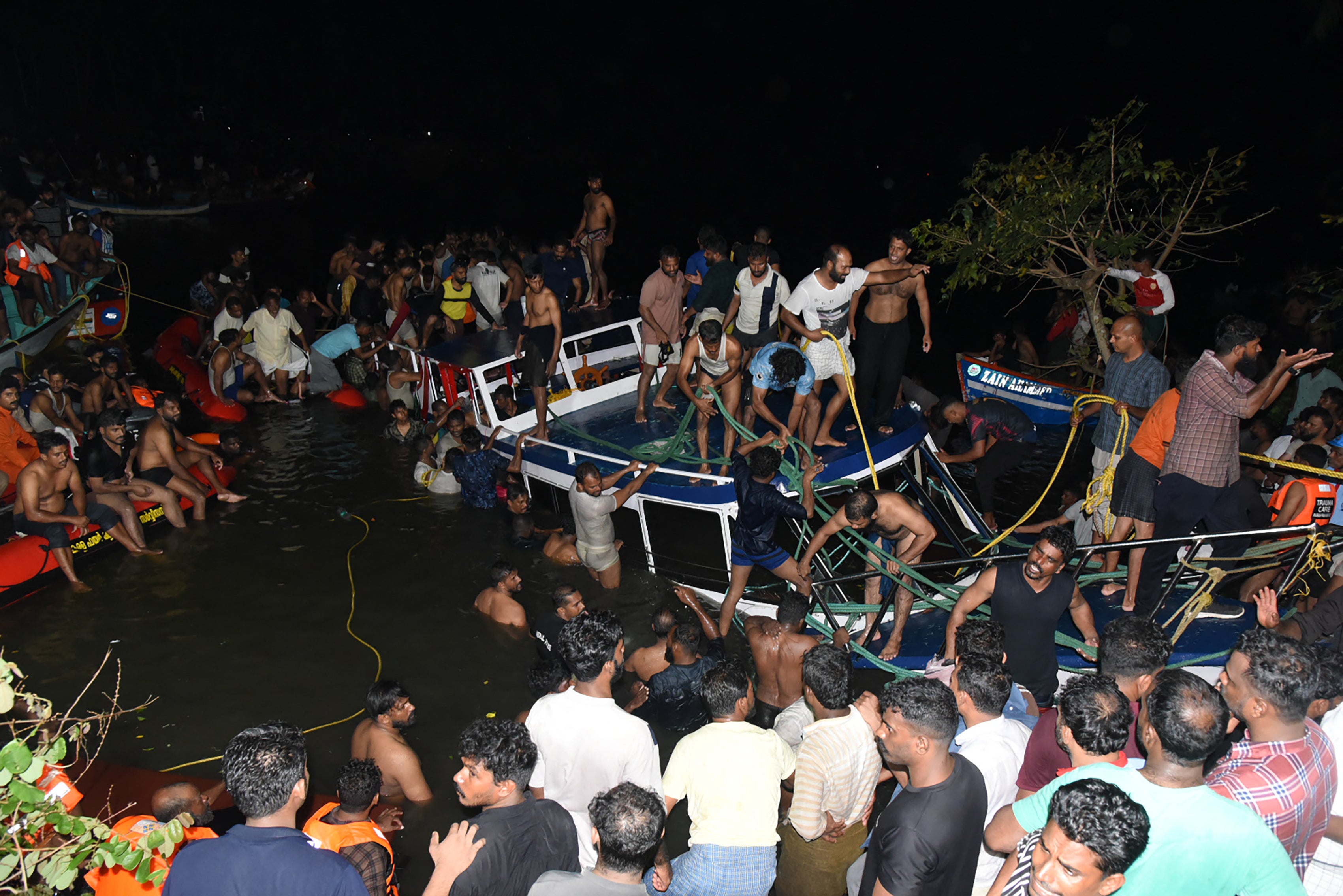 People carry out rescue operation at the site of a boat accident in Tanur in Kerala