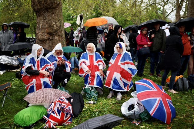 <p>People on The Mall listen to the service in the rain on loudspeakers</p>