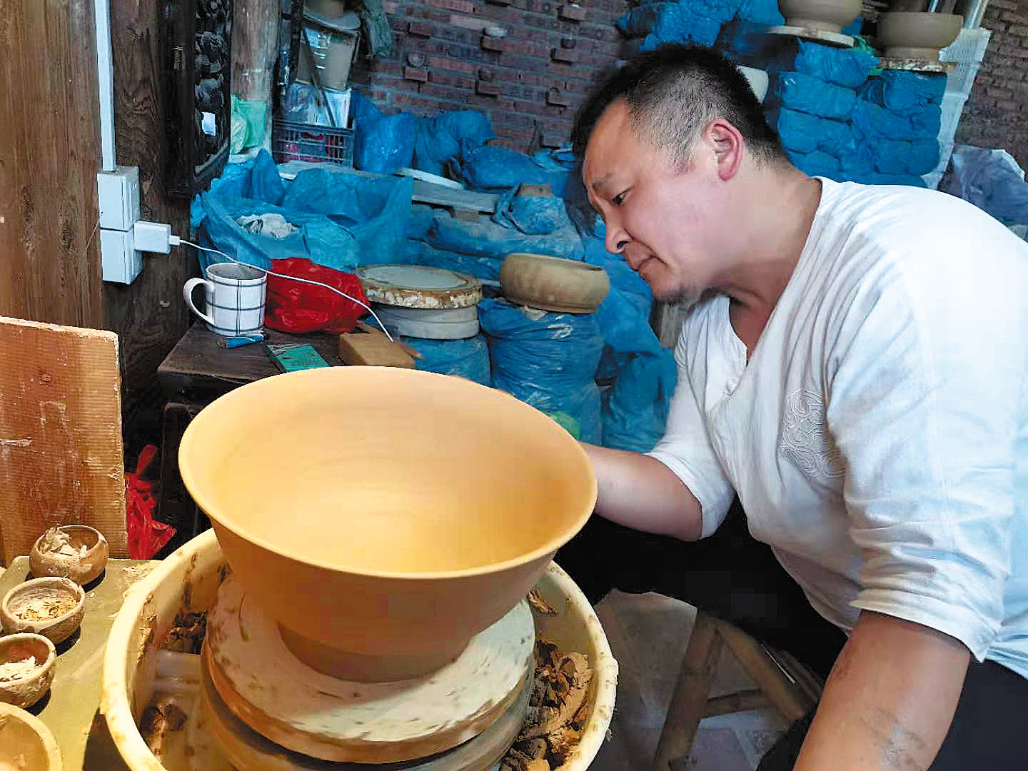Xin Zhaoguo, an inheritor of the Zibo-style coloured glaze ceramic craft, in the process of making a ceramic product
