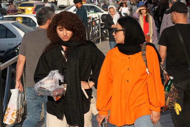 <p>A woman (left) walks around Tajrish commercial district without wearing her mandatory Islamic headscarf in northern Tehran, Iran</p>