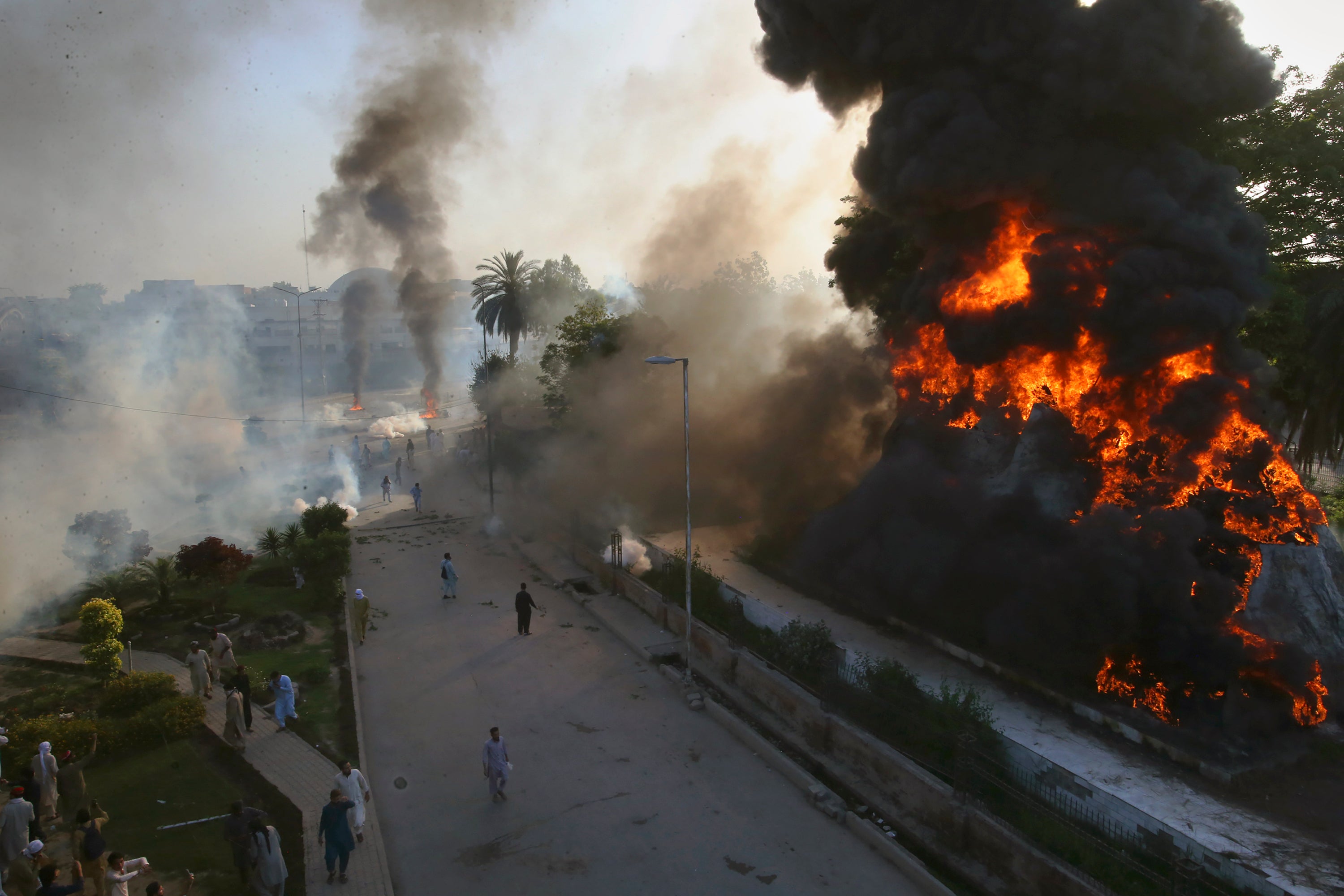 <p>Smoke erupts from a burning objects set on fire by angry supporters of Pakistan’s former Prime Minister Imran Khan</p>