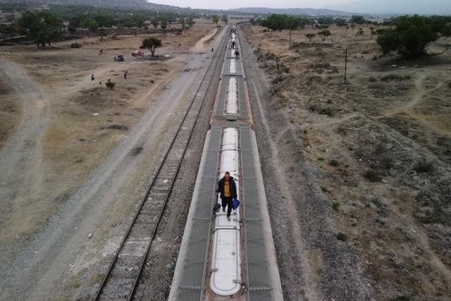 <p>Migrants, mostly from Venezuela, walk on top of railroad cars as they get ready to continue their journey to the US border</p>
