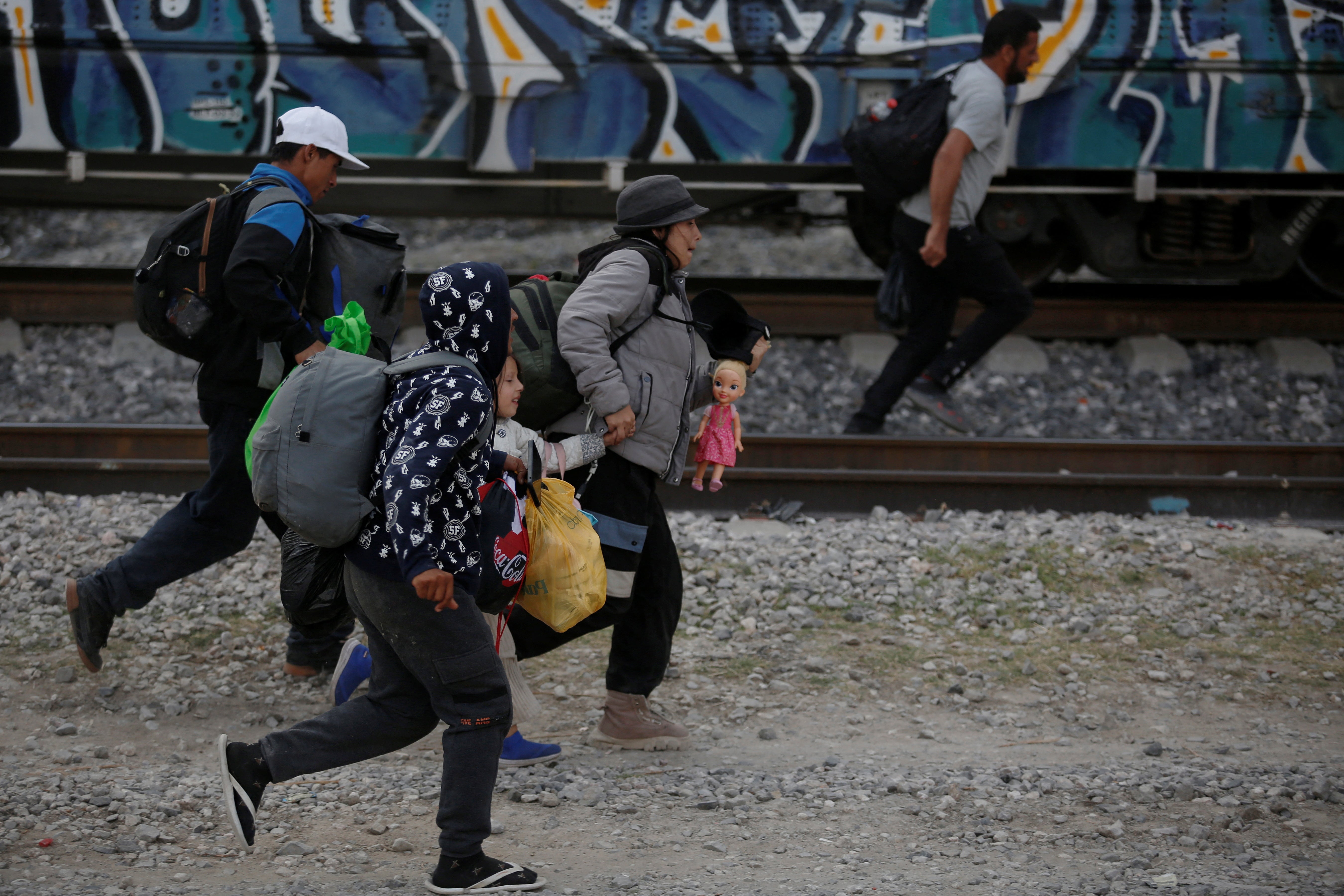 Migrants, mostly from Venezuela, run to climb on a train