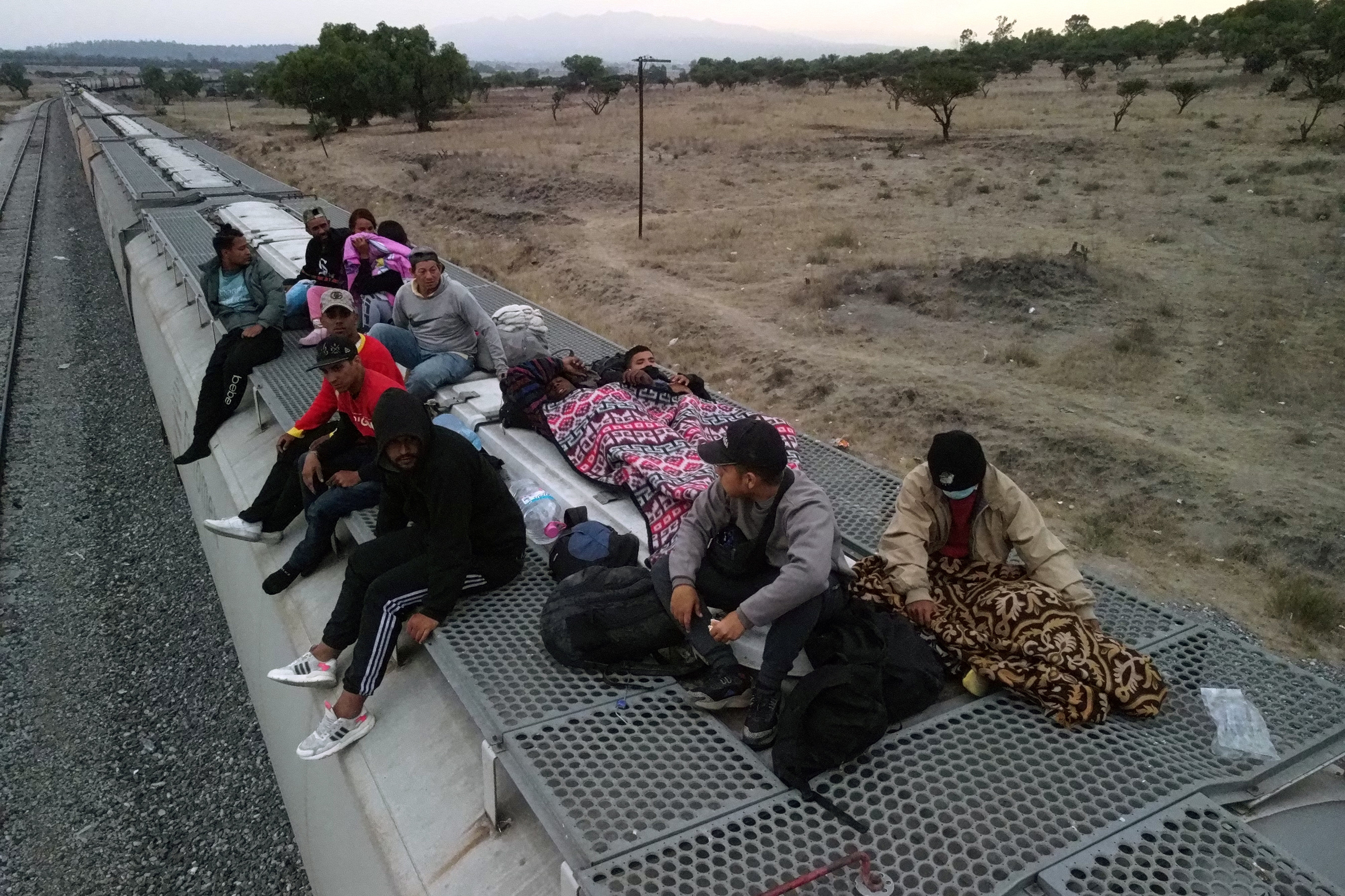 Migrants rest on top of railcars