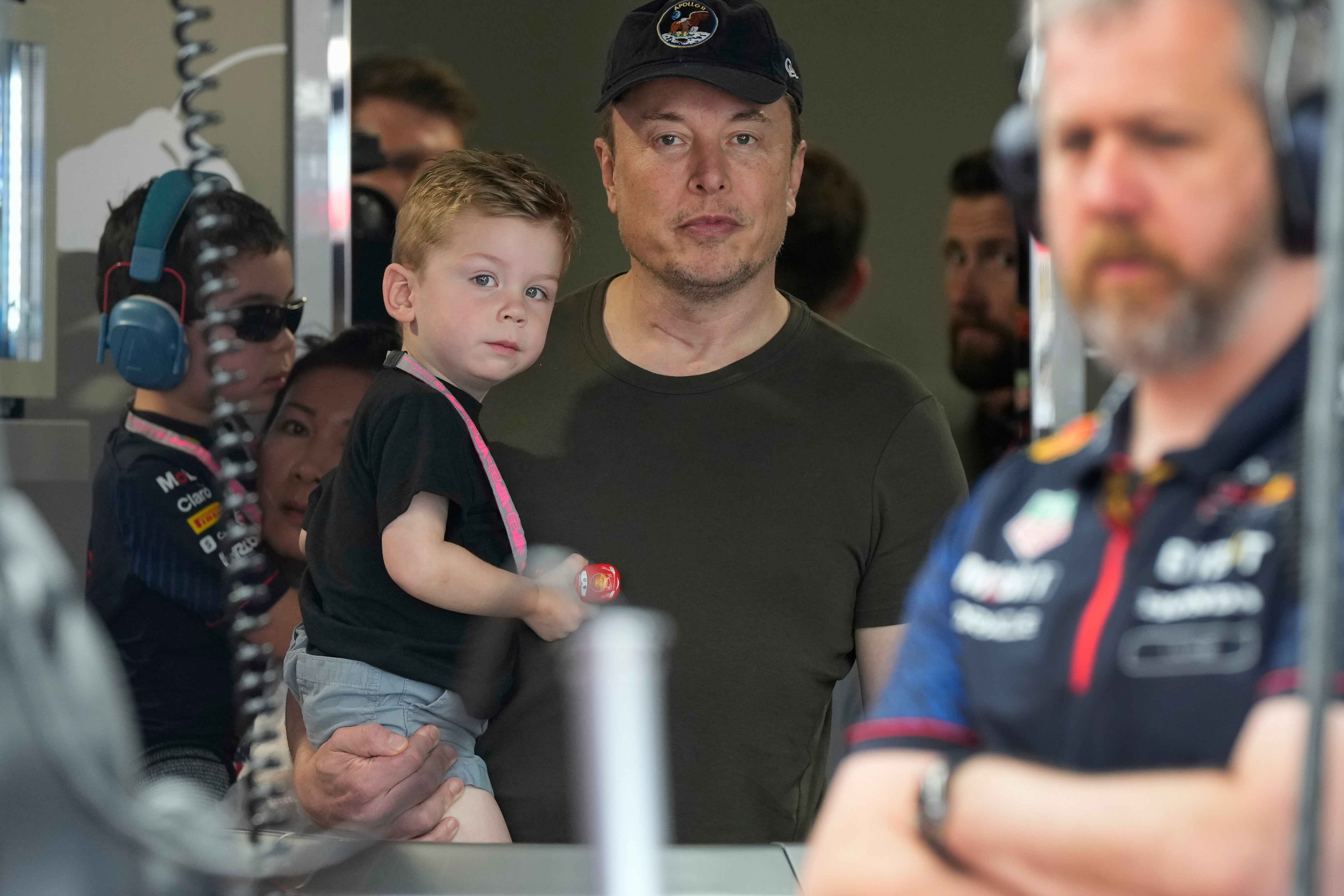 Musk holds one of his children at a Grand Prix auto race in Miami in 2023