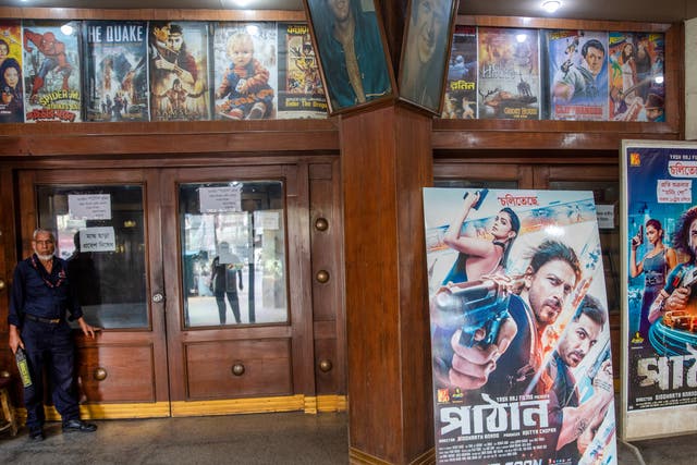 <p>A Bangladeshi security guard stands next to  posters of the Indian Hindi-language movie 'Pathaan' </p>