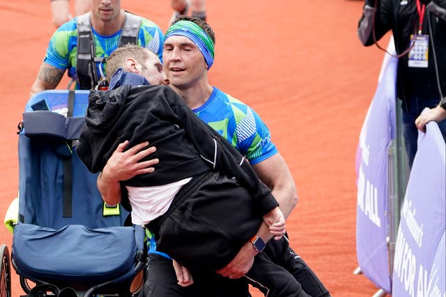 <p>Kevin Sinfield carries Rob Burrow across the finish line of the Leeds marathon in 2023 </p>