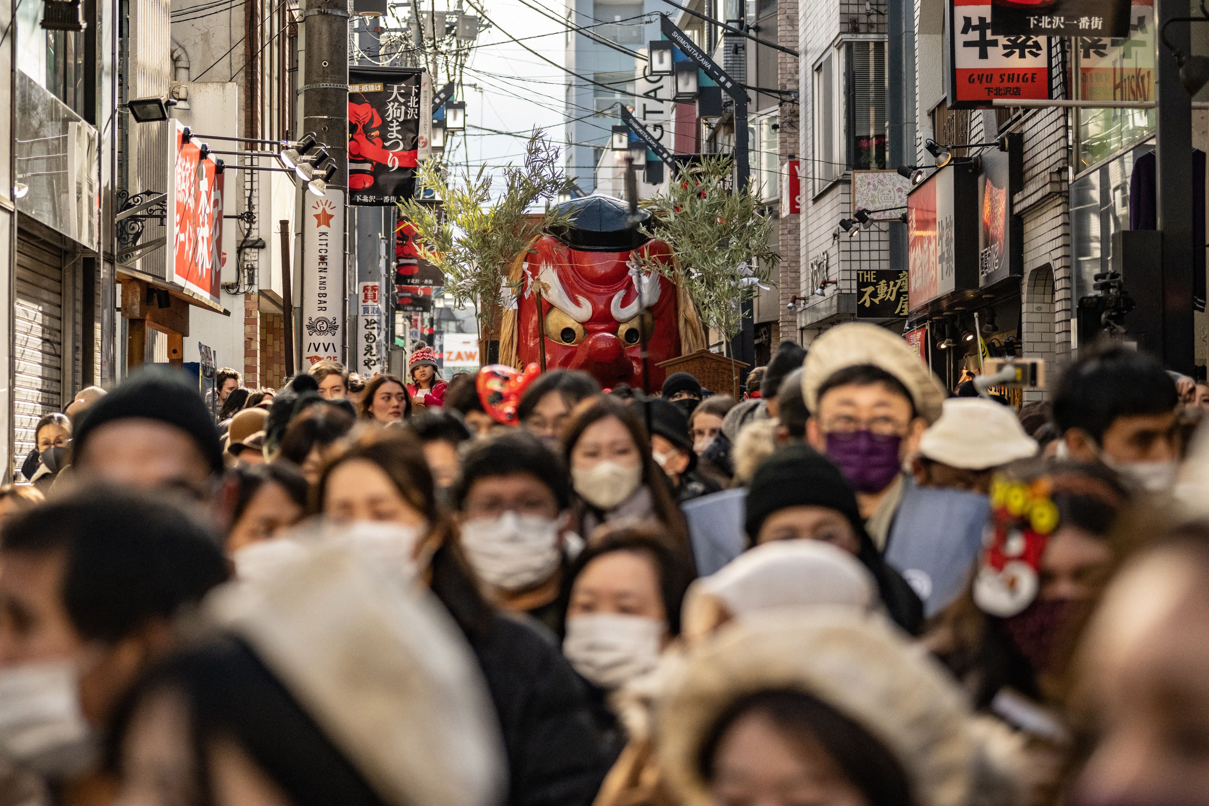 People march along a road with a large Tengu mask during the Tengu Parade, a traditional event held to drive away evil spirits and to bring good luck, at the Shimokitazawa shopping district in Tokyo on 28 January