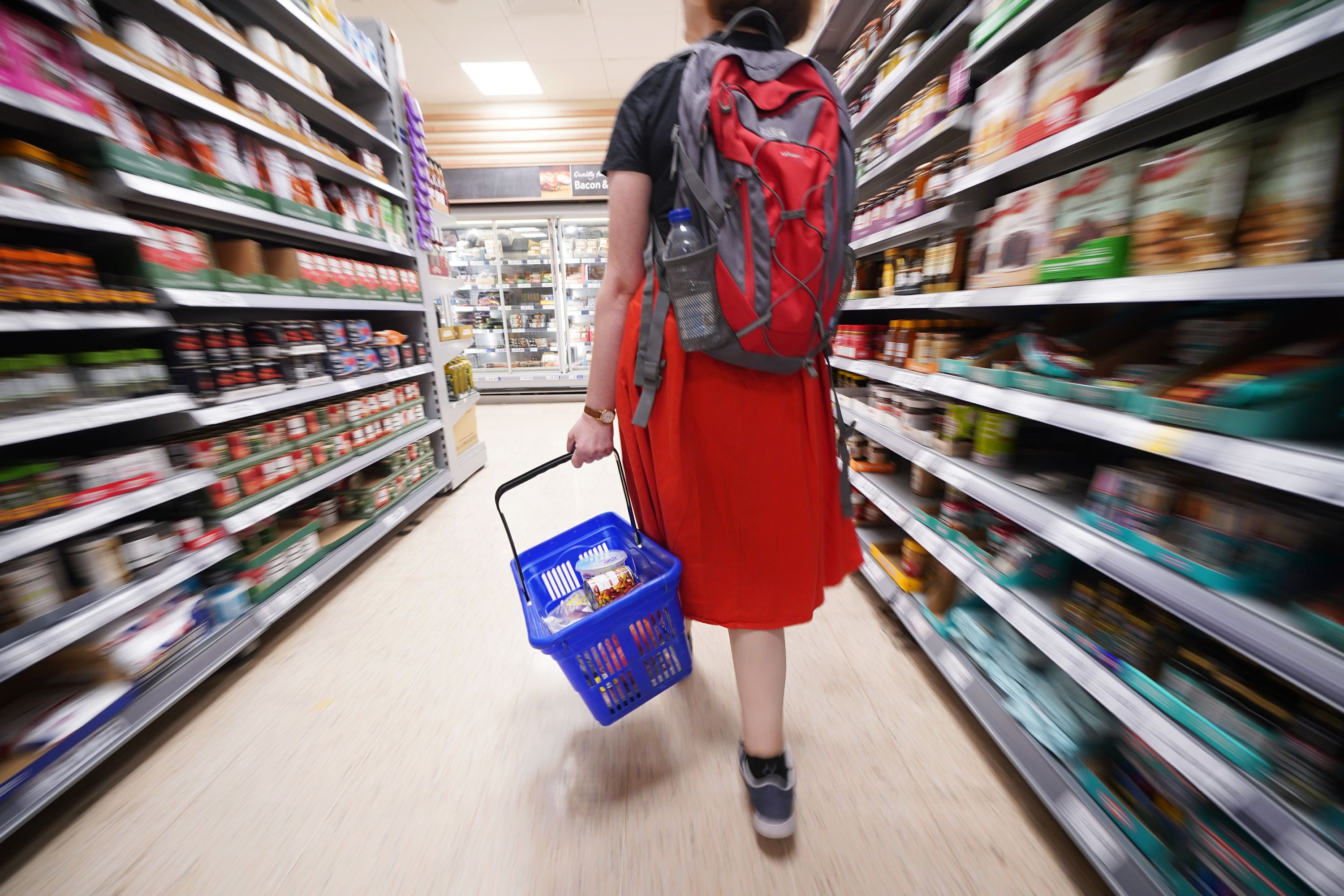 A shopper walking through the aisle of a supermarket.