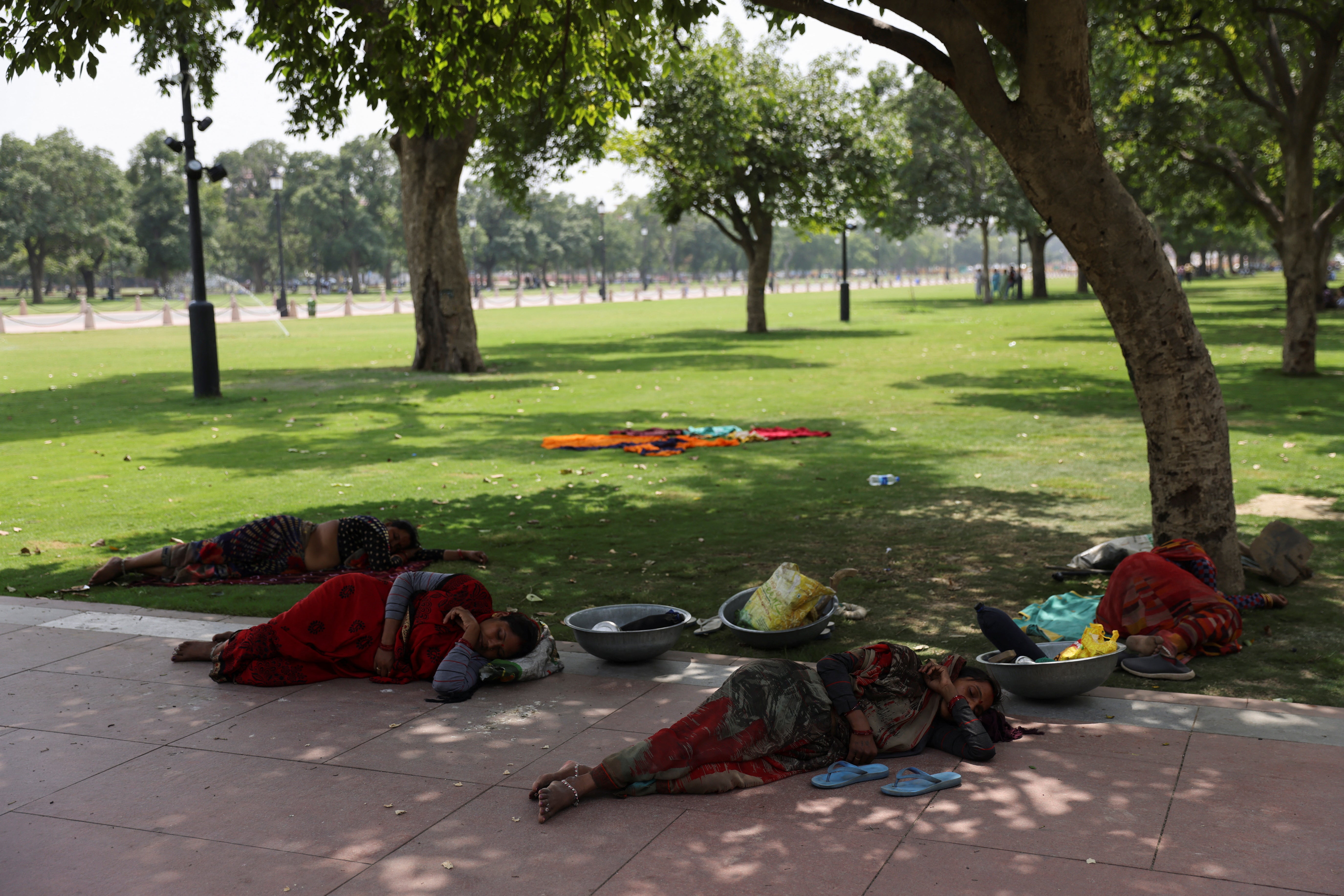 Women labourers rest in the shade of a tree near India Gate, in New Delhi, on May 15
