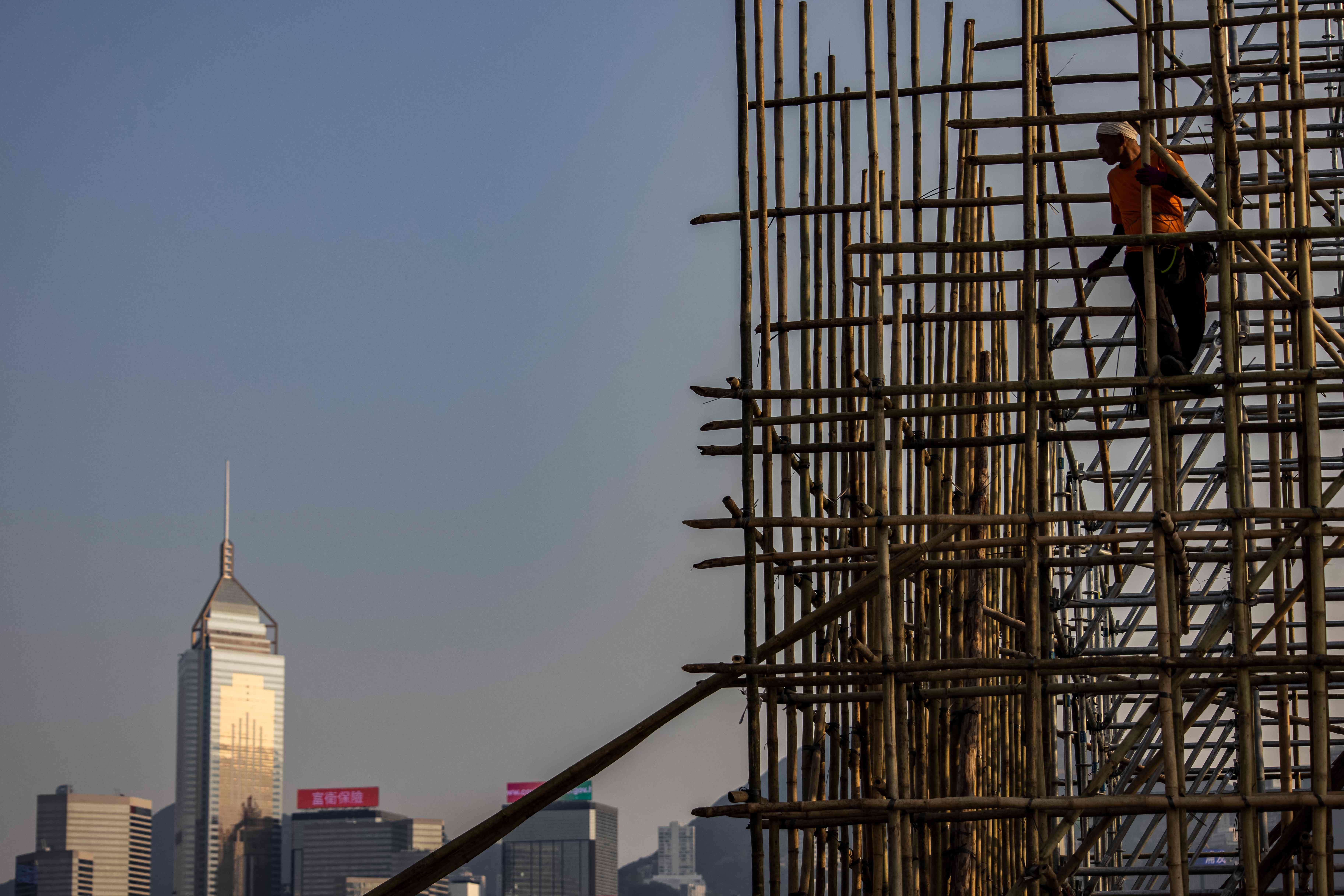 This picture taken on 1 March 2023 in Hong Kong, said to be the world’s most skyscraper-laden metropolis, shows a scaffolder standing on bamboo scaffolding
