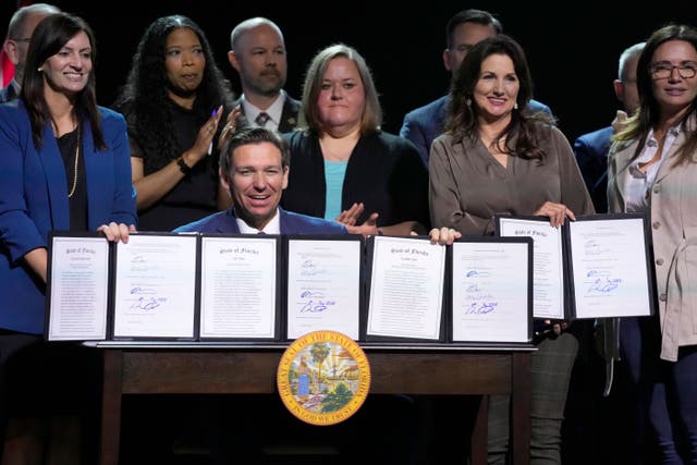 <p>Florida Gov. Ron DeSantis holds up bills he signed during a bill signing ceremony at the Coastal Community Church at Lighthouse Point, Tuesday, May 16, 2023</p>