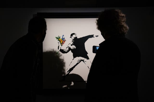 People observe a Banksy artwork (Aaron Chown/PA)