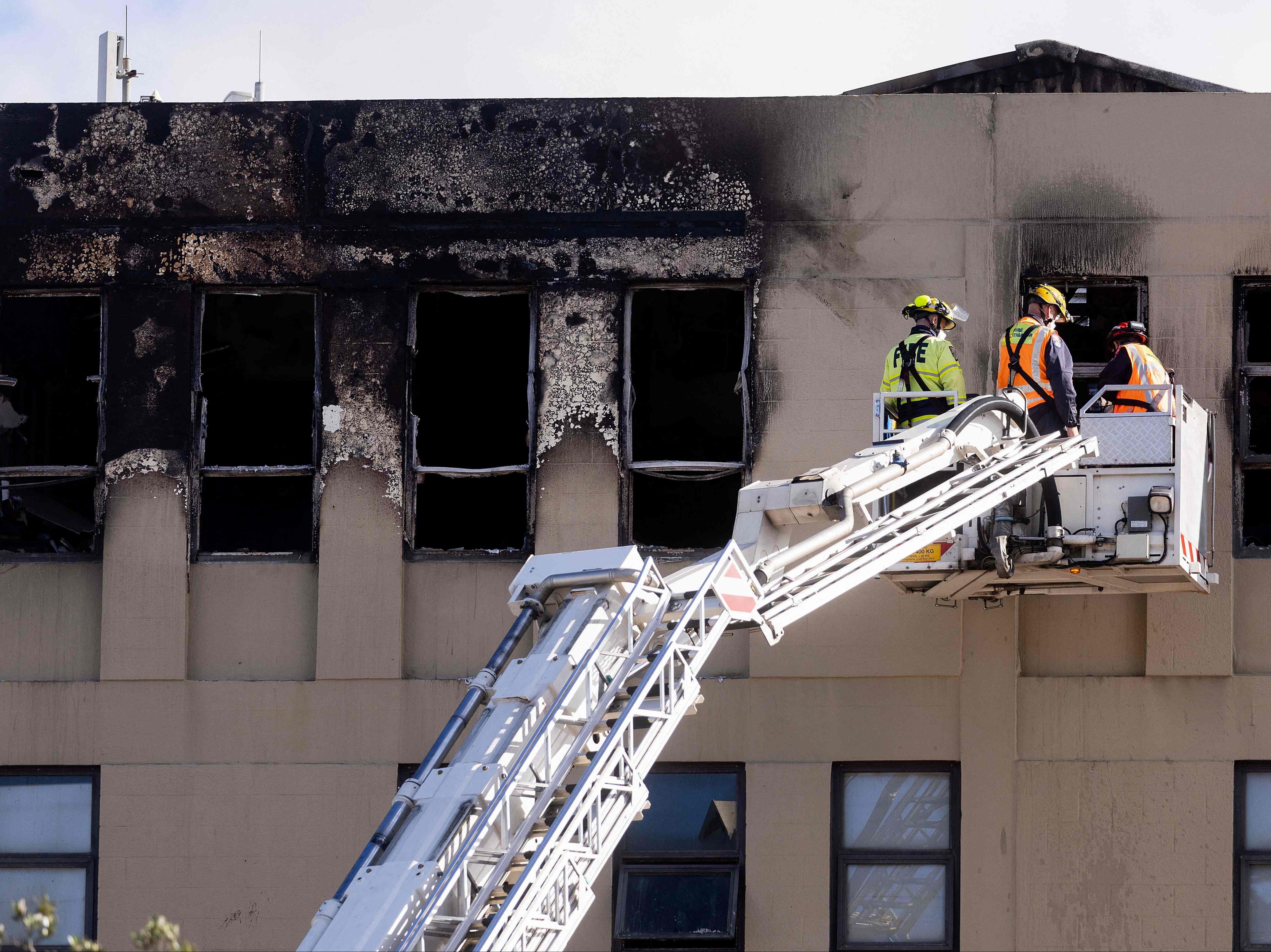Firefighters inspect the Loafers Lodge hostel where a fire broke out