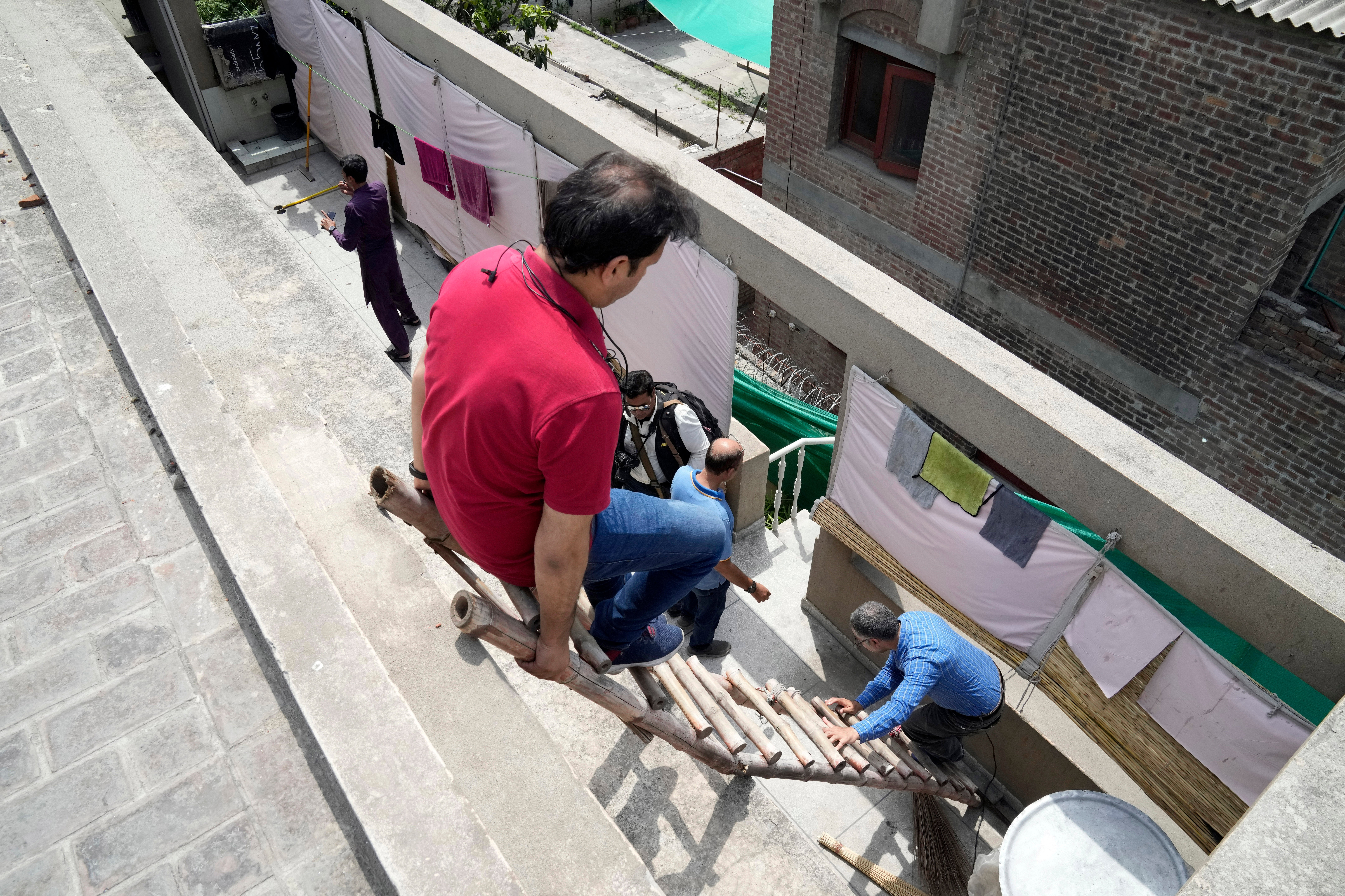 Members of the media climb down from the roof of Pakistan’s former PM Imran Khan’s house in Lahore on 18 May