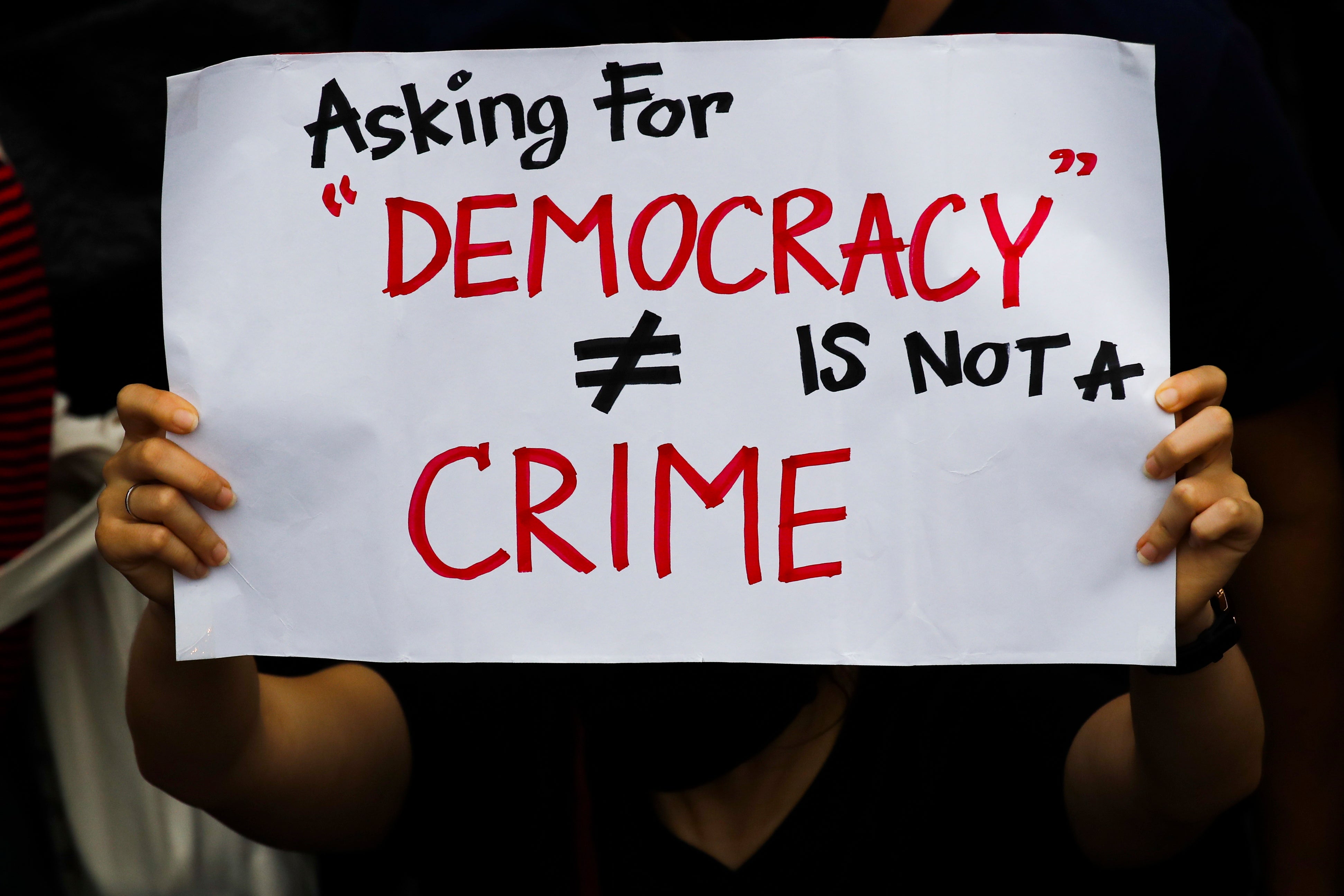 File: A pro-democracy protester holds a placard ‘Asking For Democracy Is Not A Crime’ during an anti-government protest in Bangkok