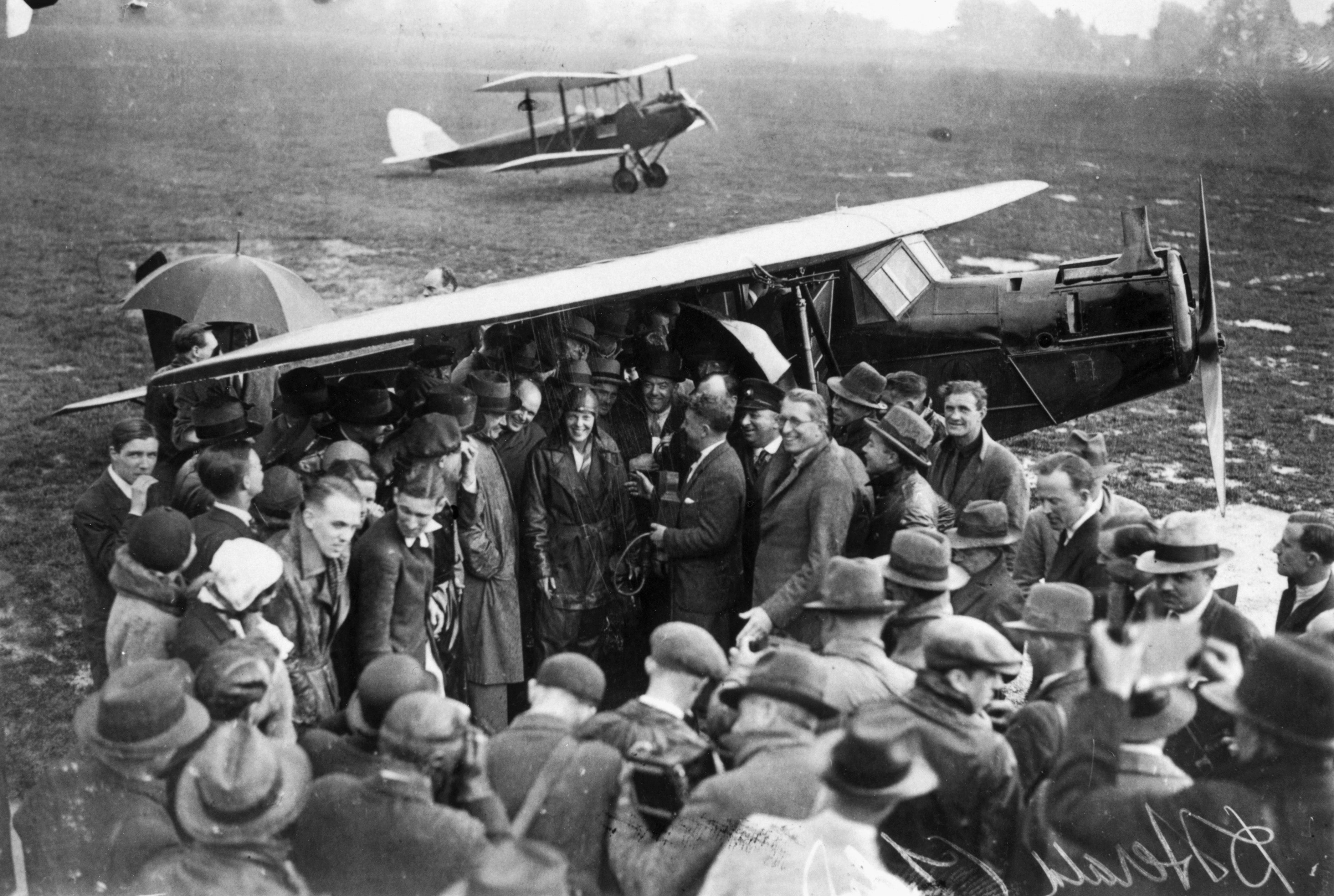 American aviator Amelia Earhart (1898 - 1937) (centre) is surrounded by a crowd of wellwishers and pressmen on arrival at Hanworth airfield after crossing the Atlantic.
