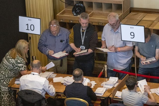 Green Party NI leader Mal O’Hara, centre, tallying ballots as ballot boxes are opened in Belfast City Hall (Liam McBurney/PA)