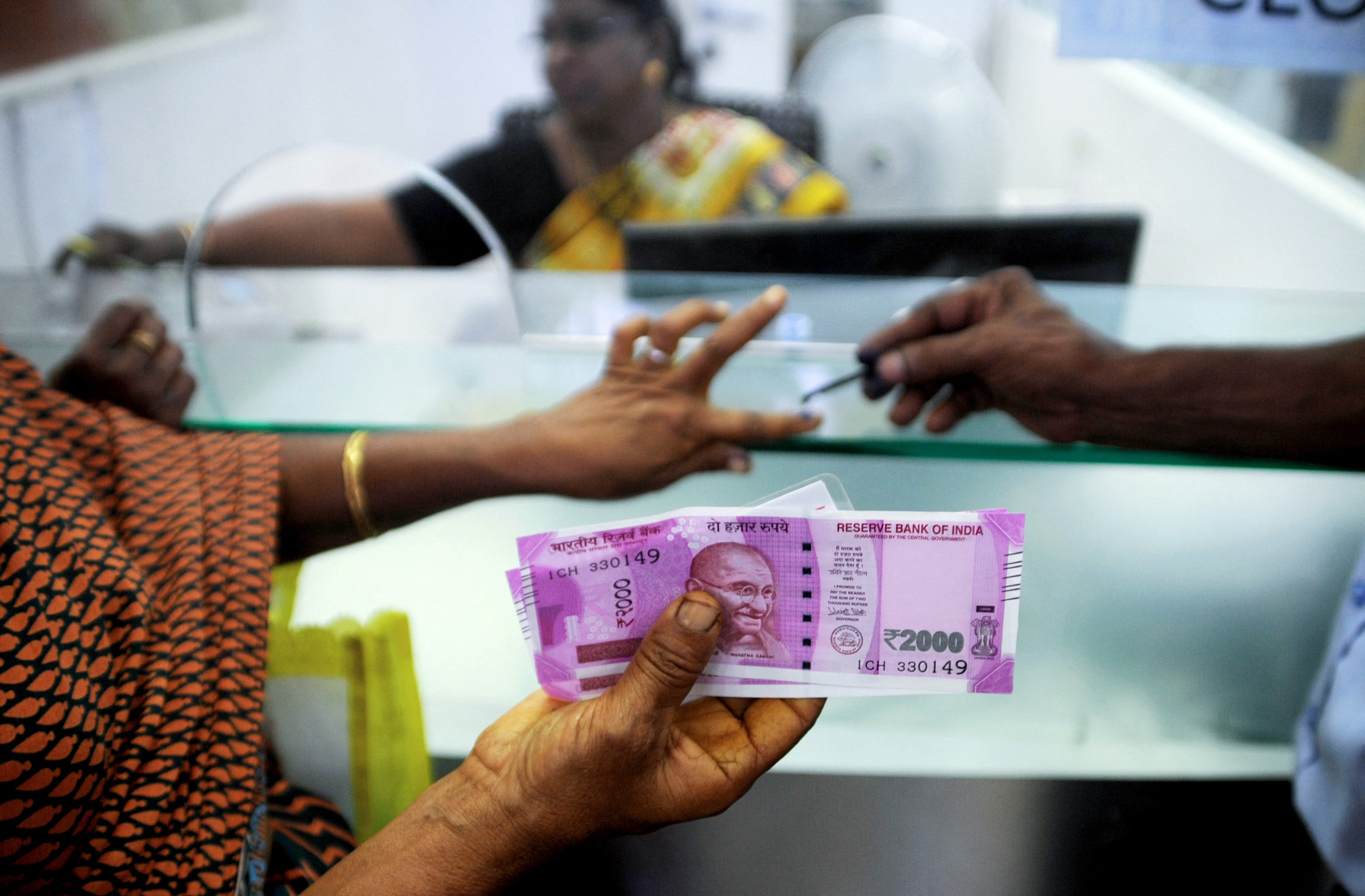 File. An Indian woman displays her 2000 rupee notes as she has her finger inked with indelible ink after exchanging withdrawn 500 and 1000 rupee banknotes at a bank in Chennai in 2016