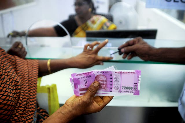 <p>File. An Indian woman displays her 2000 rupee notes as she has her finger inked with indelible ink after exchanging withdrawn 500 and 1000 rupee banknotes at a bank in Chennai in 2016 </p>