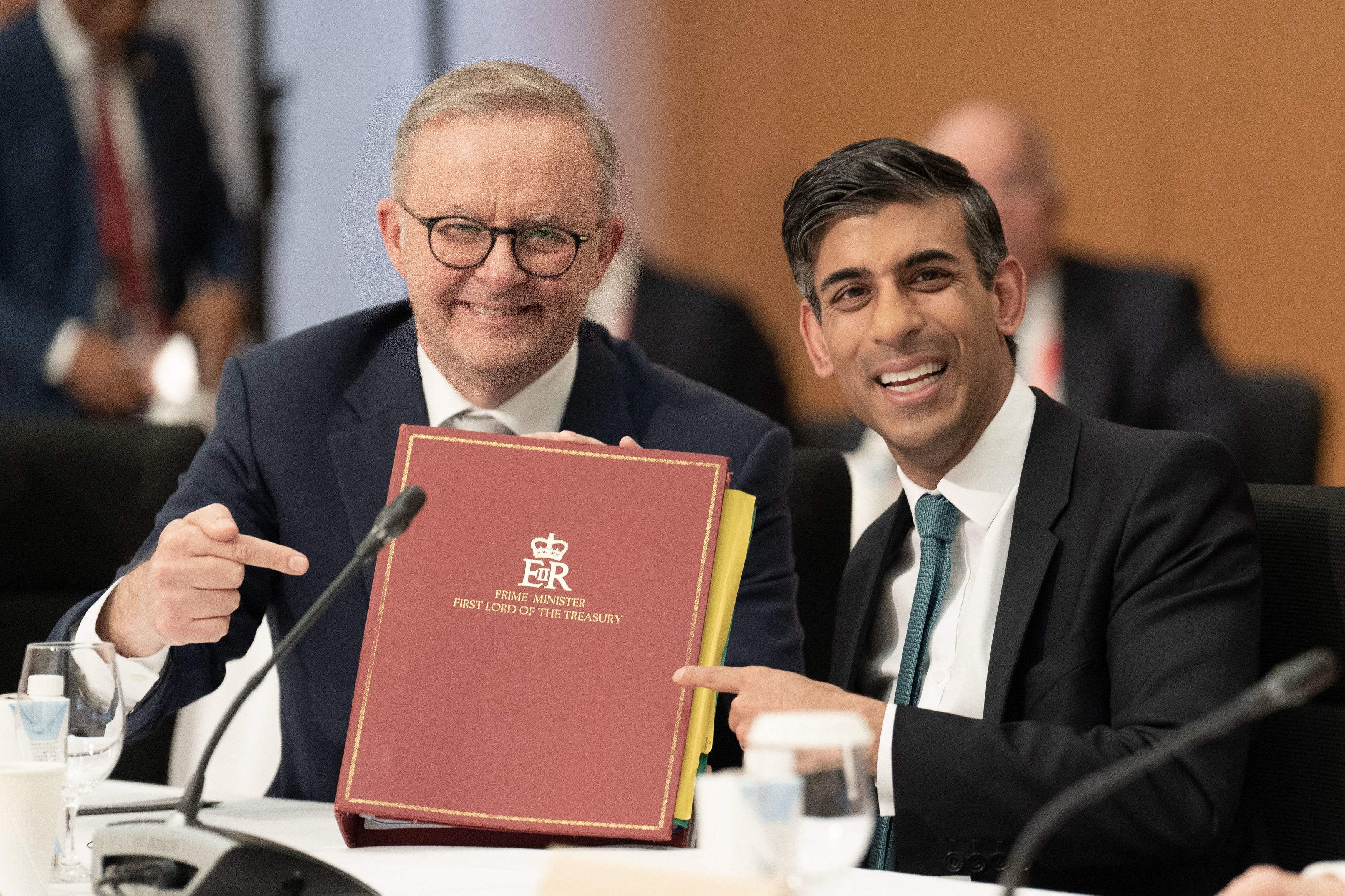Australia's prime Minister Anthony Albanese (L) holds British prime minister Rishi Sunak's ministerial folder at a working session during the G7 Leaders' Summit in Hiroshima