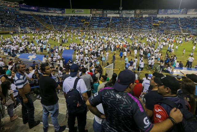 <p>Fans are forced on to the pitch during a crush at the Monumental Stadium in Cuscatlan, El Salvador (Milton Flores/AP)</p>
