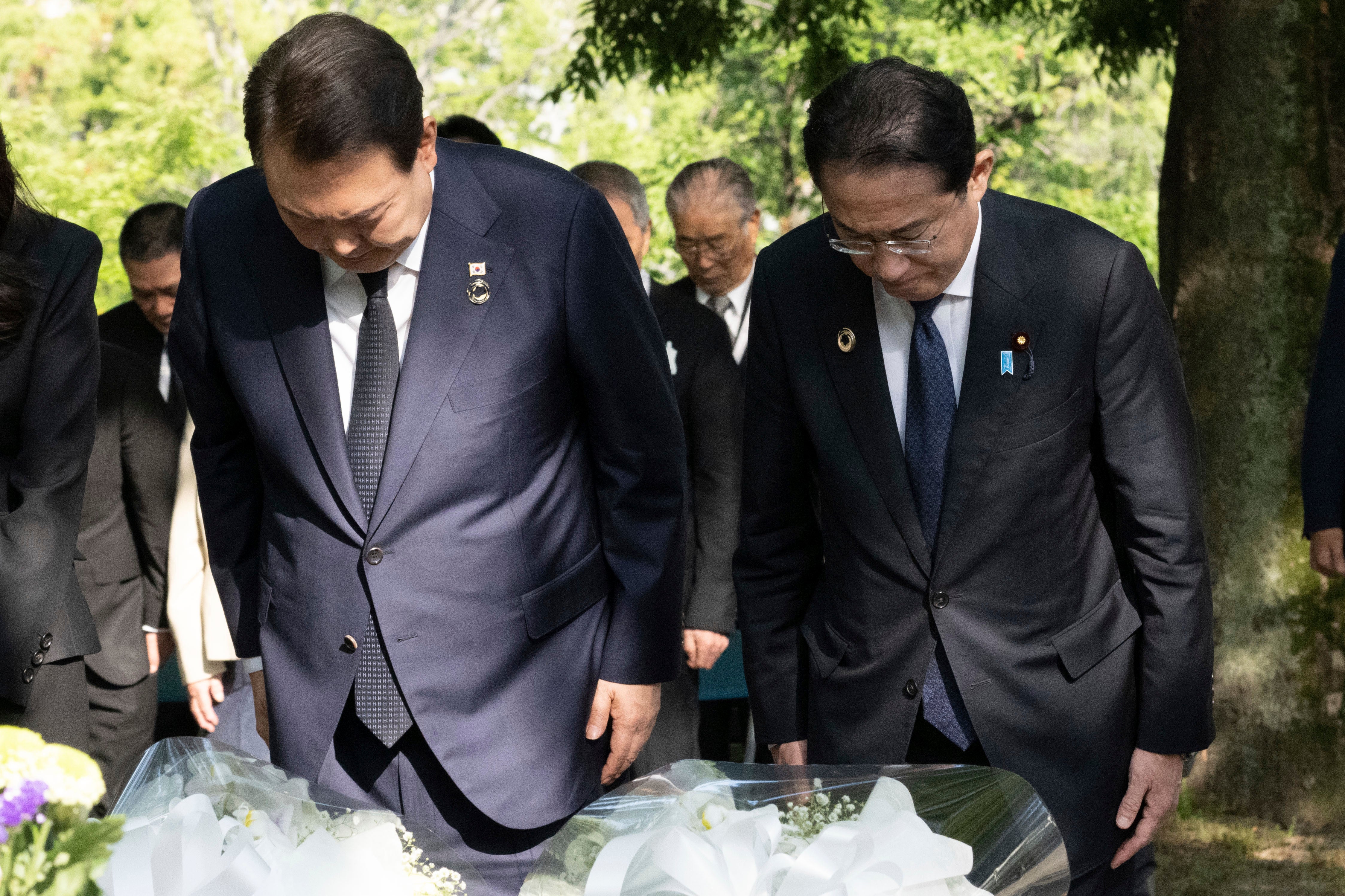 South Korean president Yoon Suk Yeol (L) with Japan’s prime minister Fumio Kishida bow after laying flowers at the Korean Atomic Bomb Victims Memorial Memorial