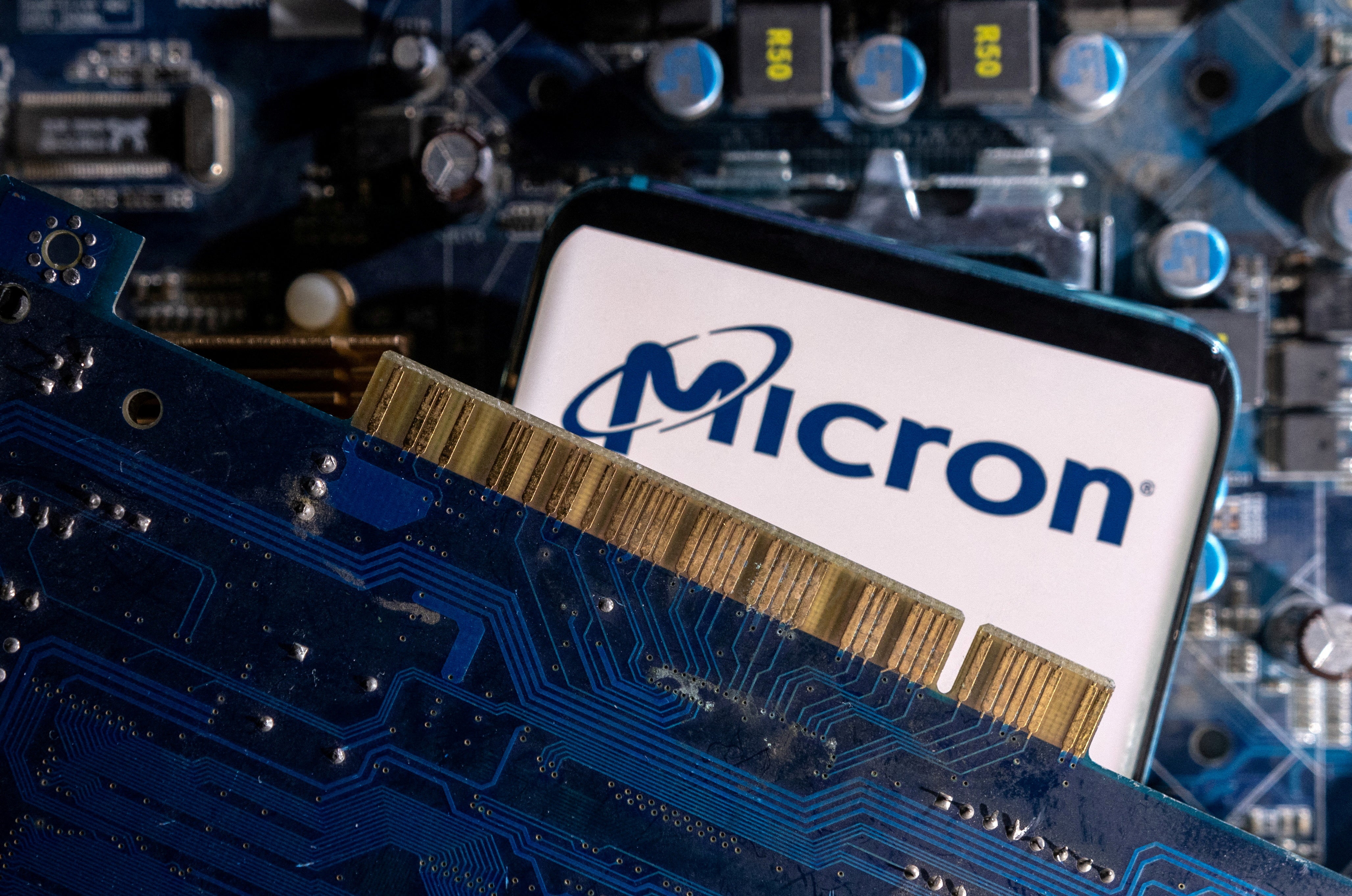 A smartphone with a displayed Micron logo is placed on a computer motherboard
