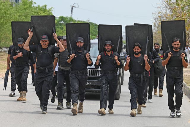 <p>Security personnel with ballistic shields escort a vehicle carrying former Pakistan's prime minister Imran Khan as he leaves after appearing before an anti-terrorism court</p>
