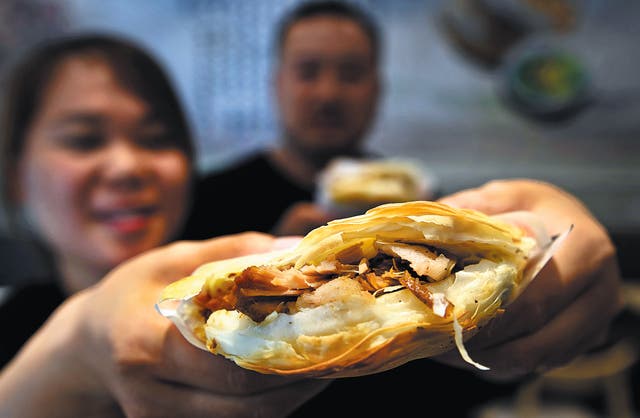 <p>A customer displays <em>roujiamo</em> she bought from an eatery in Tongguan county, Shaanxi province </p>