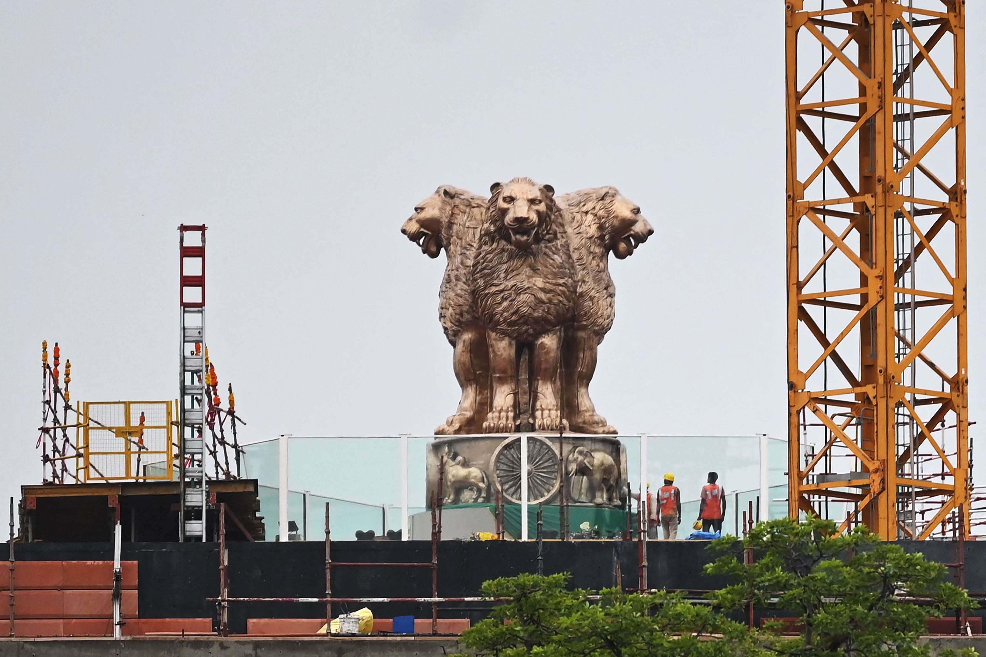 File: Workers stand next to the newly inaugurated ‘National Emblem’ installed on the roof of the new Indian parliament building in New Delhi