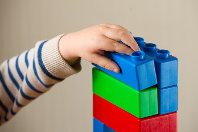 <p>A  school age child playing with plastic building blocks. </p>
