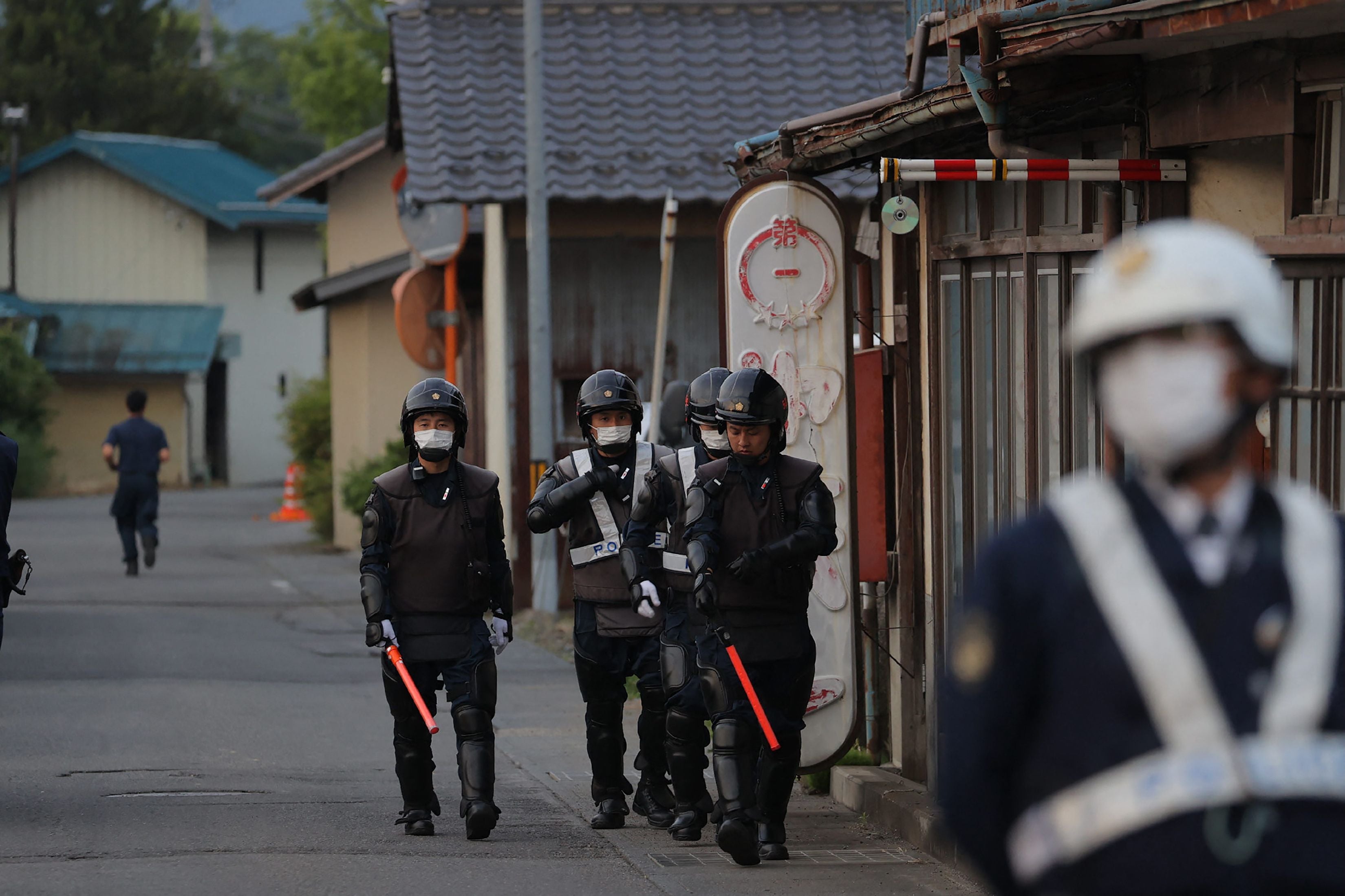 Japanese police officers are seen near the scene of a standoff where a suspect was holed up inside a building