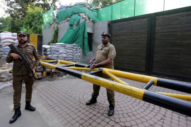 <p>Pakistani security officials stand guard as Lahore Commissioner Muhammad Ali Randhawa searches the residence of former Pakistani Prime Minister Imran Khan at Zaman Park on 19 May</p>