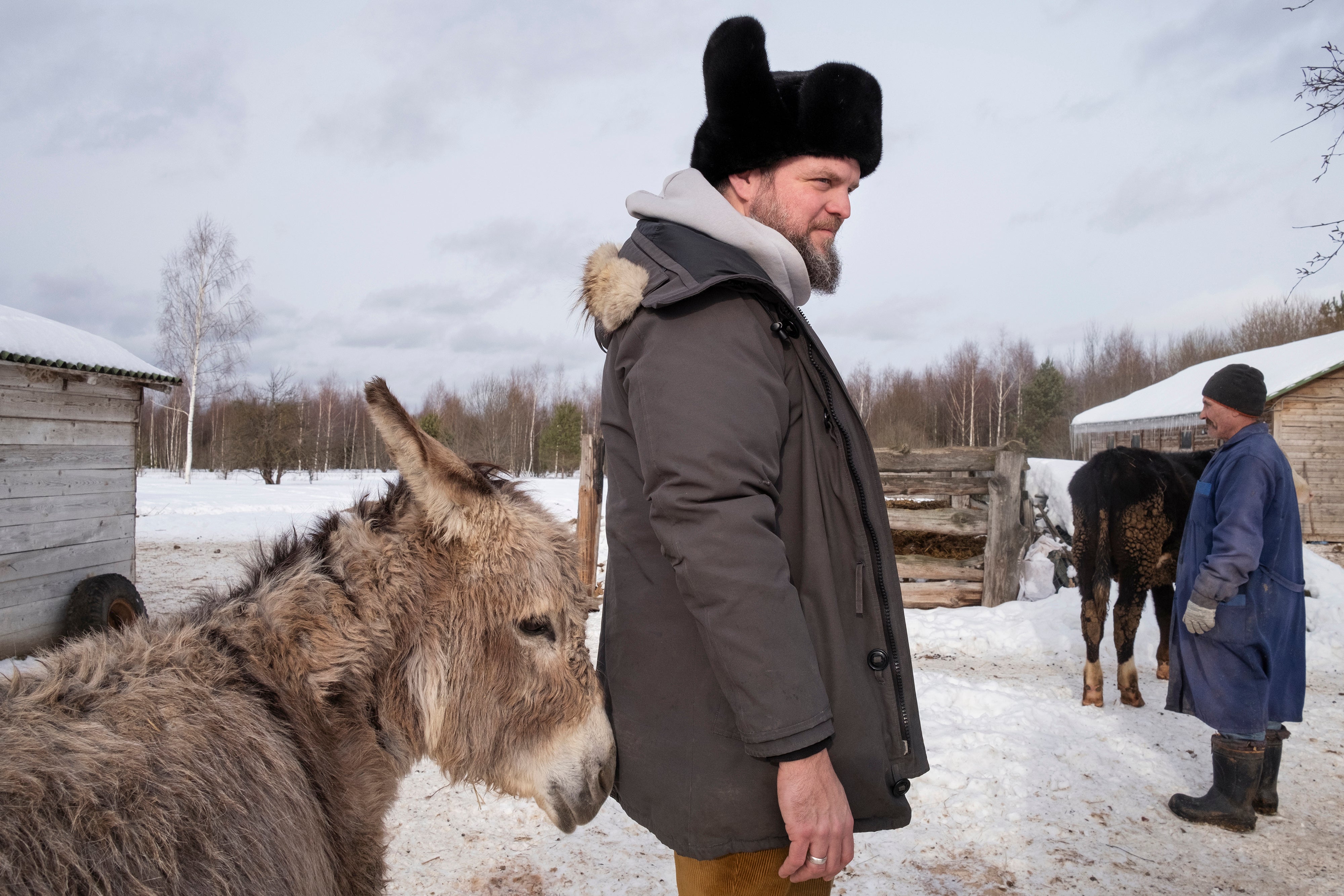 A donkey nudges Boris Akimov at his farm