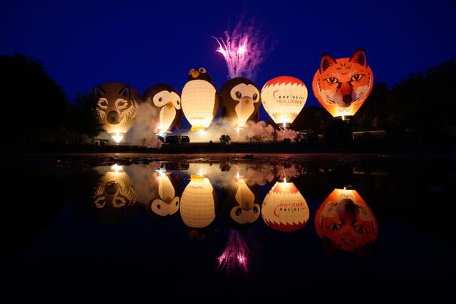 Balloons light up as they are tethered to the ground during the night glow at the Isle of Wight Balloon Festival at Robin Hill Country Park (Andrew Matthews/PA)