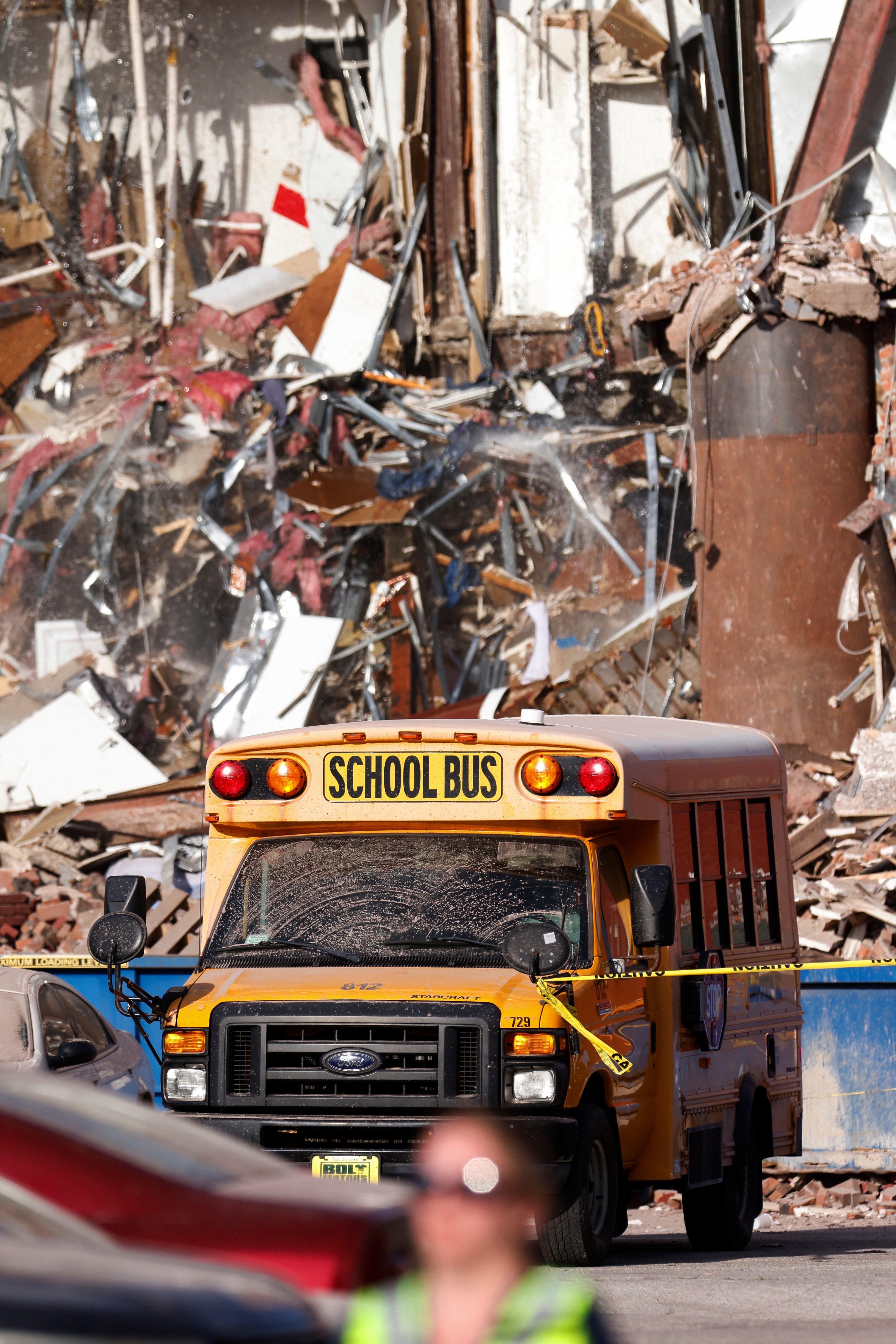 A school bus drives past the rubble after a building collapsed in Davenport, Iowa
