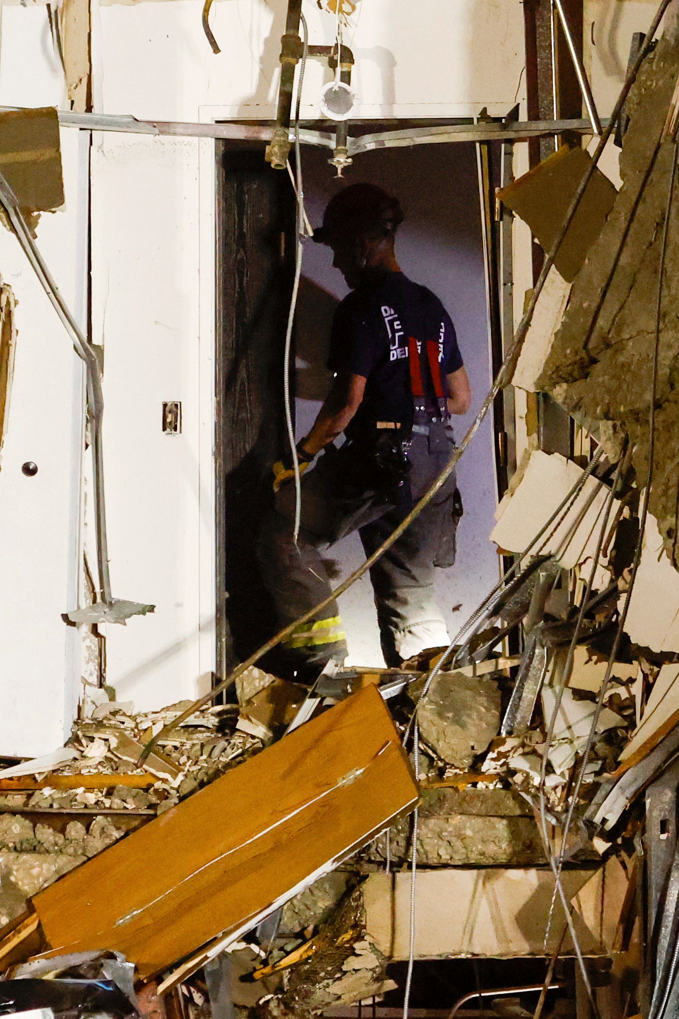 Un bombero trepa entre los escombros del edificio derrumbado