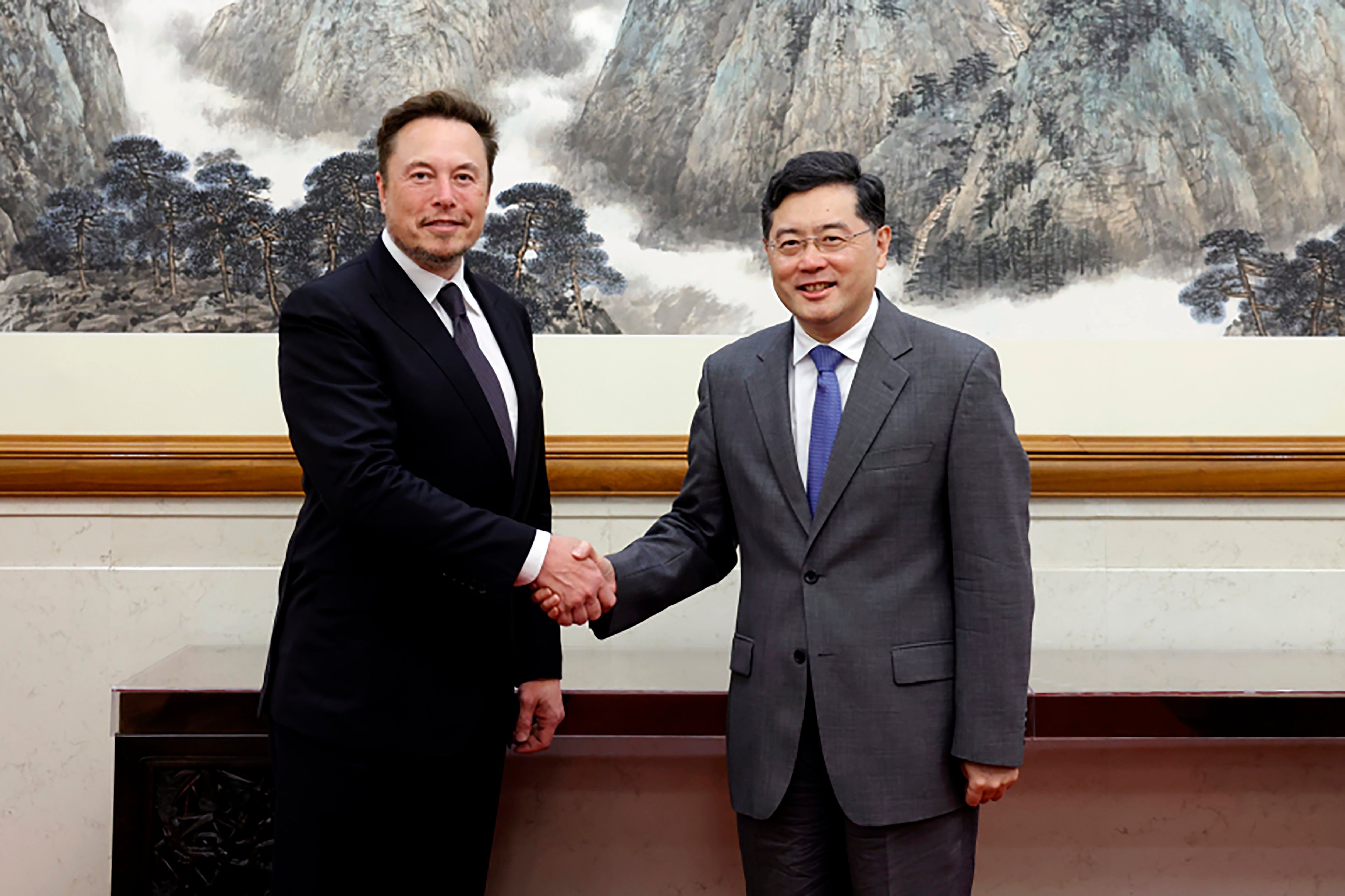 China's foreign minister Qin Gang, right, poses for photos with Tesla chief Elon Musk