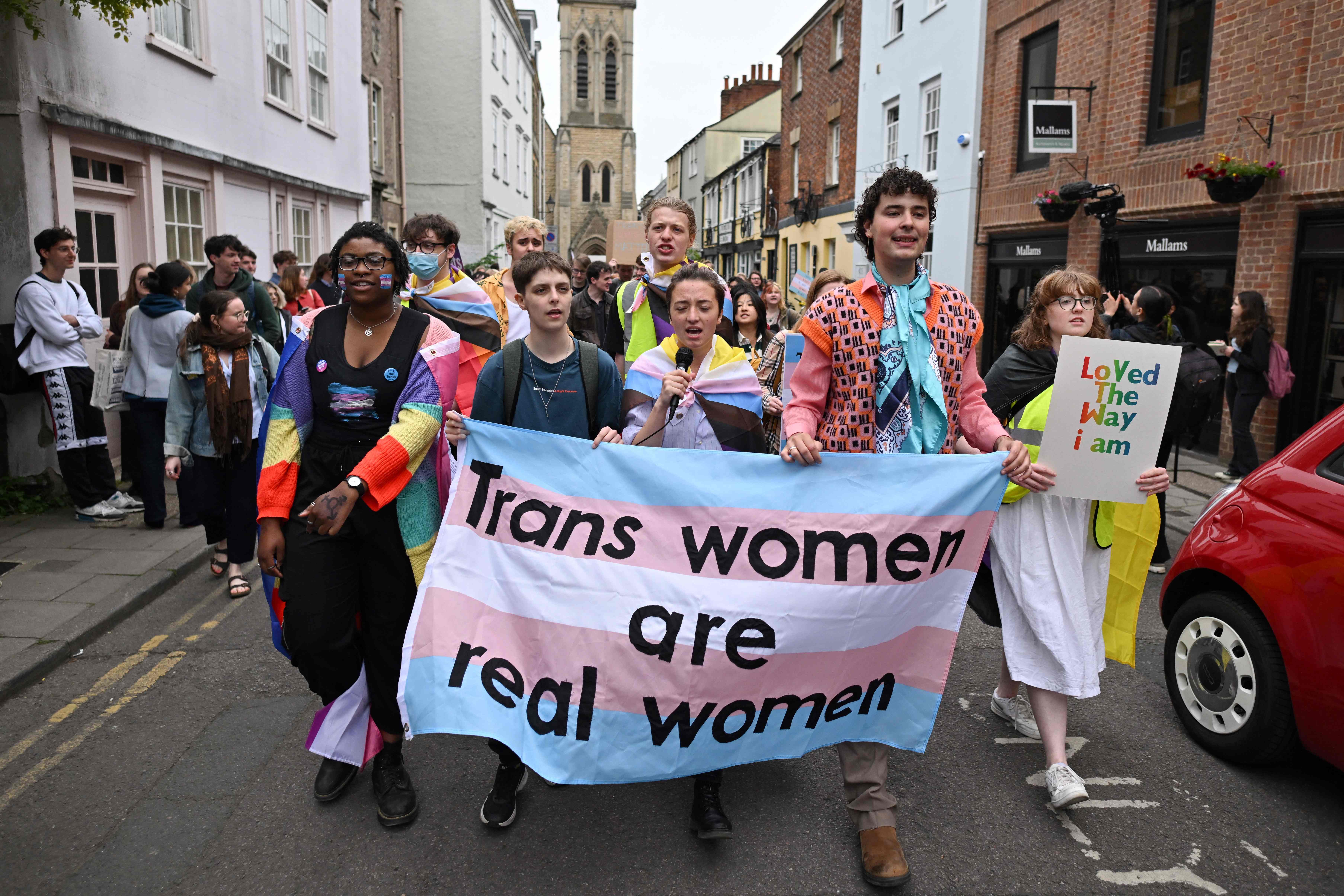 President of Oxford University LGBTQ+ Society Amiad Haran Diman (second right) holds a banner during protests against an appearance by feminist philosopher Kathleen Stock on Tuesday