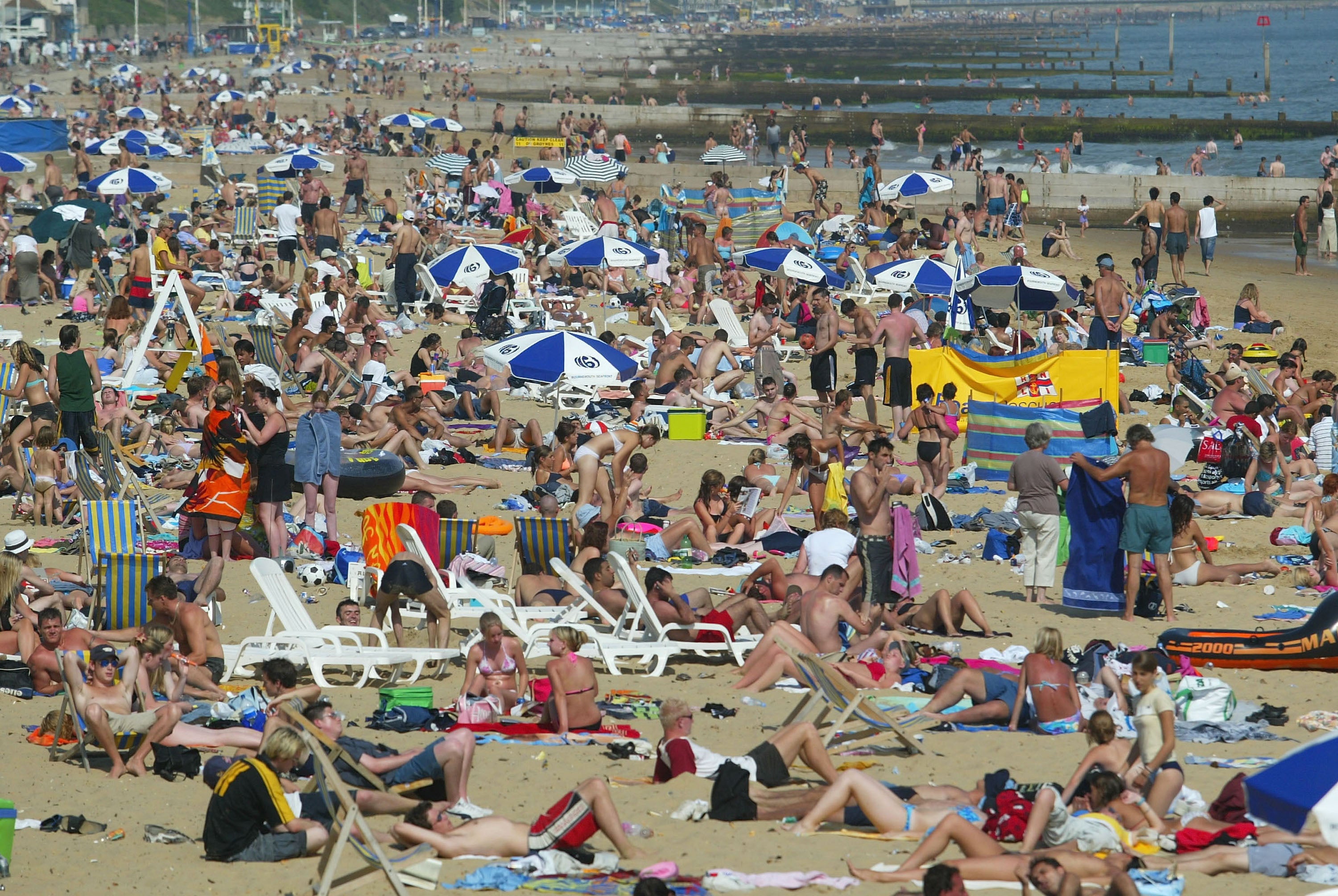 <p>People bask in the sun on Bournemouth beach on July 15, 2003 in Bournemouth, England</p>