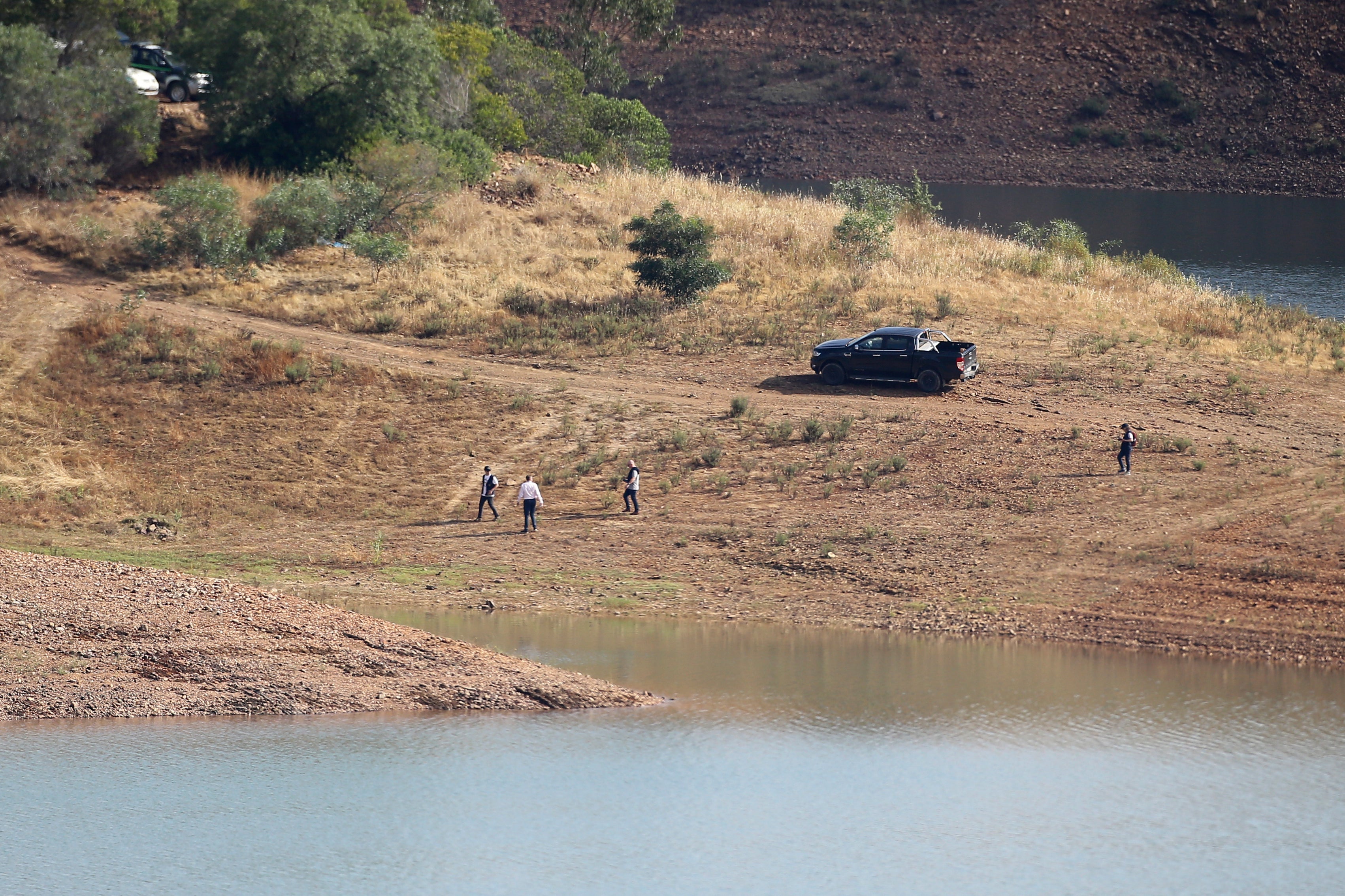 A police search team walk on the shore of the Arade dam near Silves, Portugal