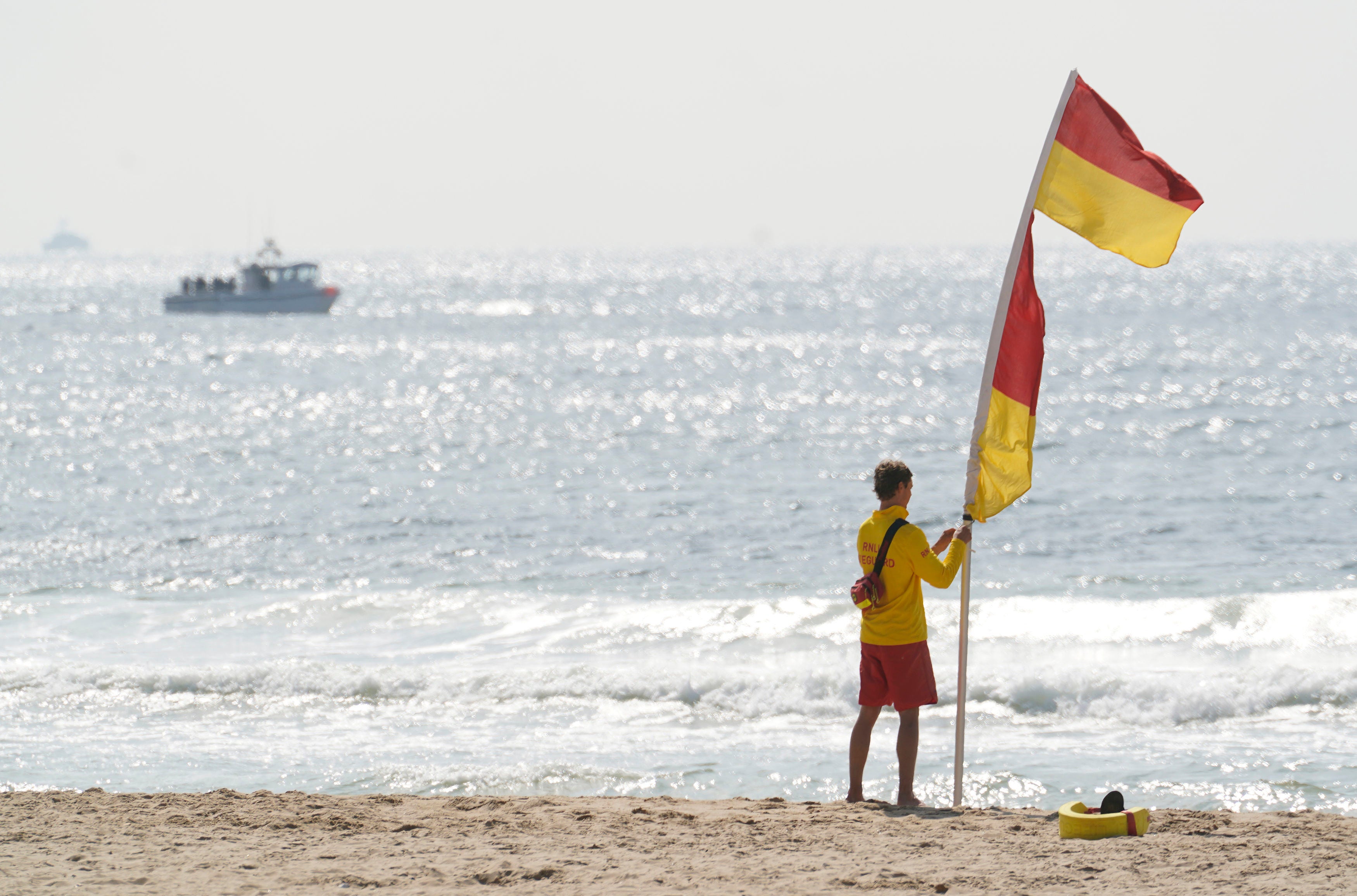 A lifeguard raises a supervised swimming flag on Bournemouth Beach a day after tragedy