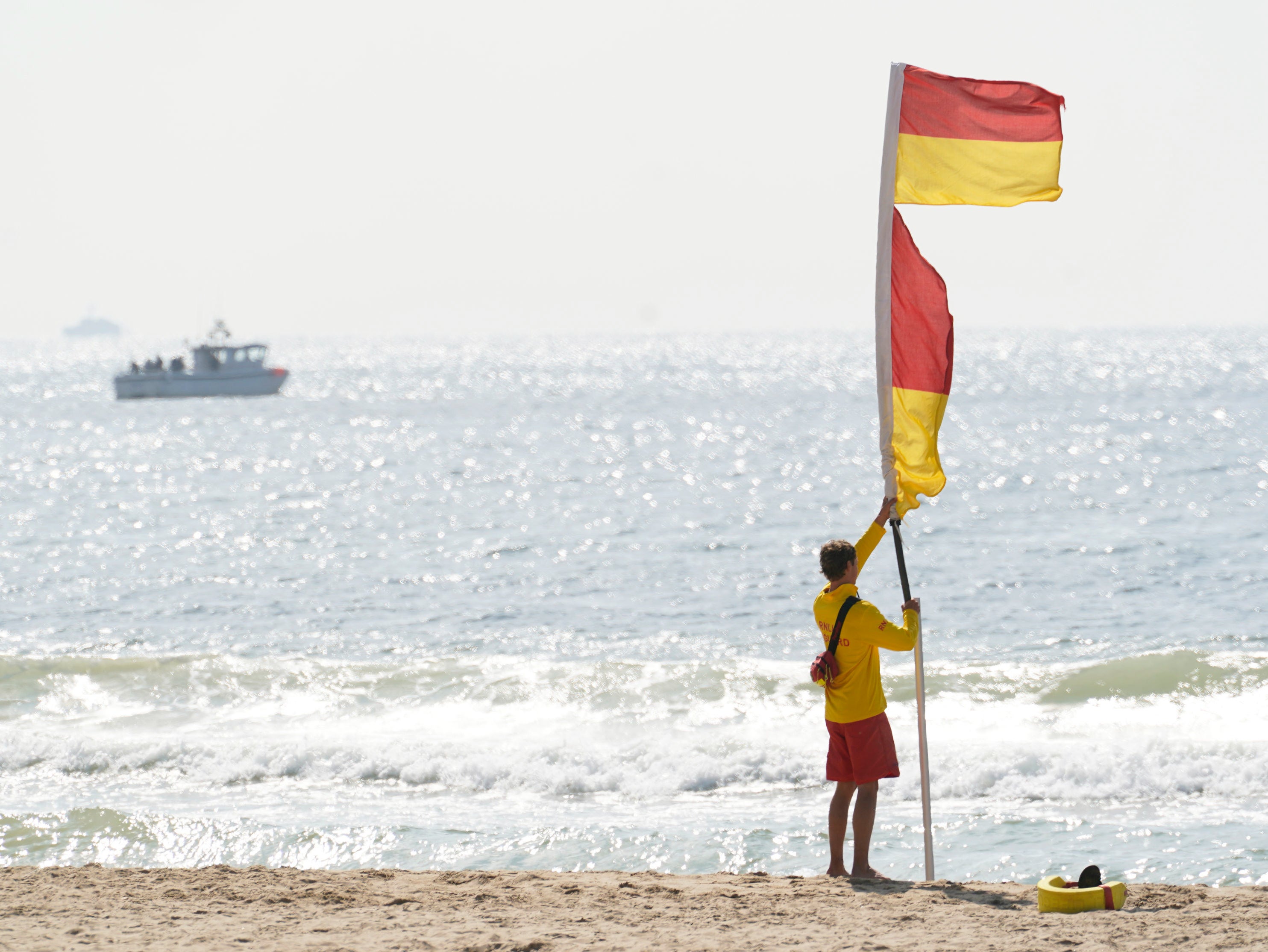 <p>RNLI lifeguards put up flags on the beach </p>