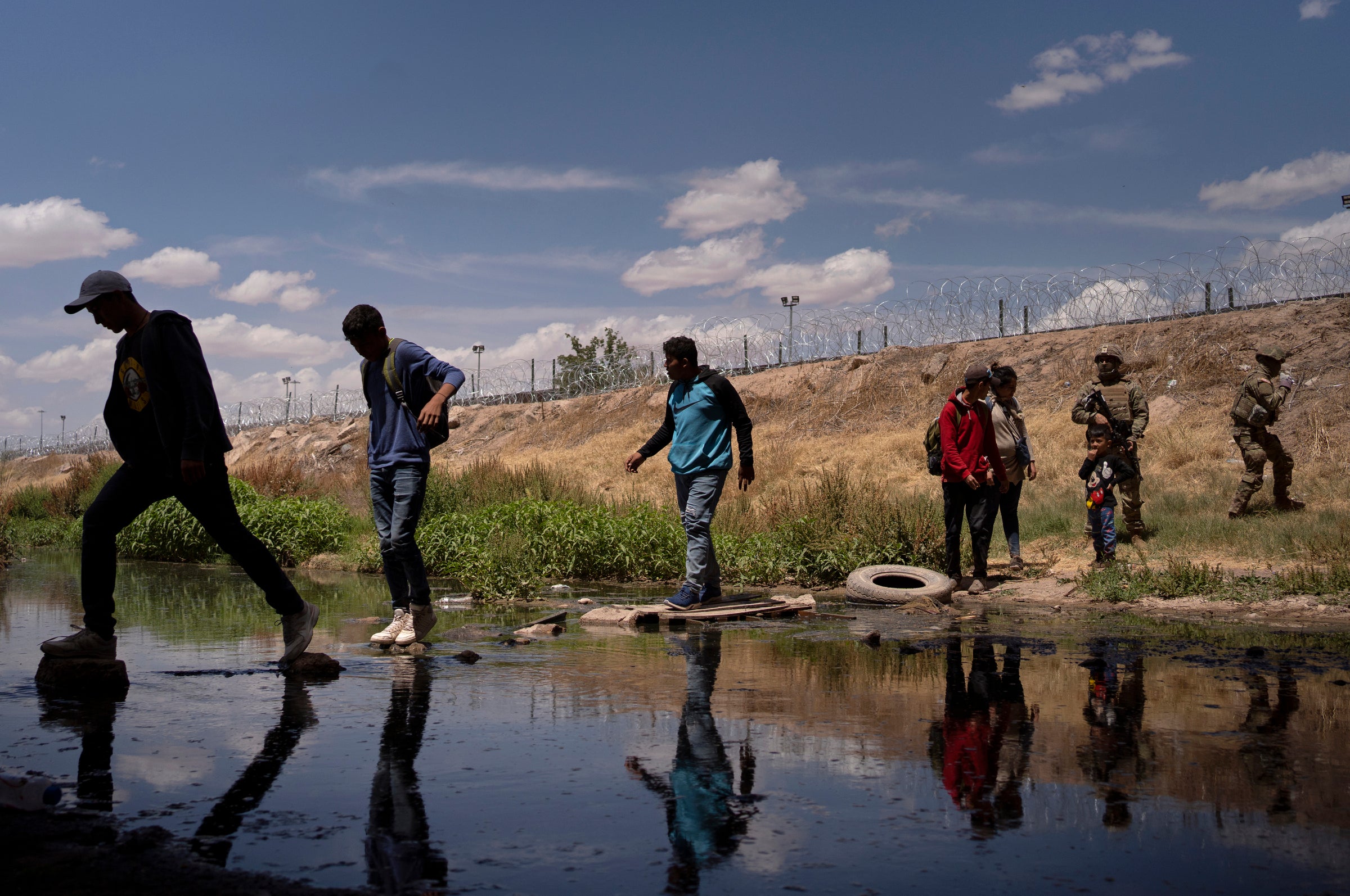 Migrants go back across the Rio Grande at Ciudad Juárez on 13 May after Texas National Guard members tell them to leave the spot where they had gathered under the Ysleta-Zaragoza Bridge at El Paso in hopes of surrendering themselves to seek asylum in the United States